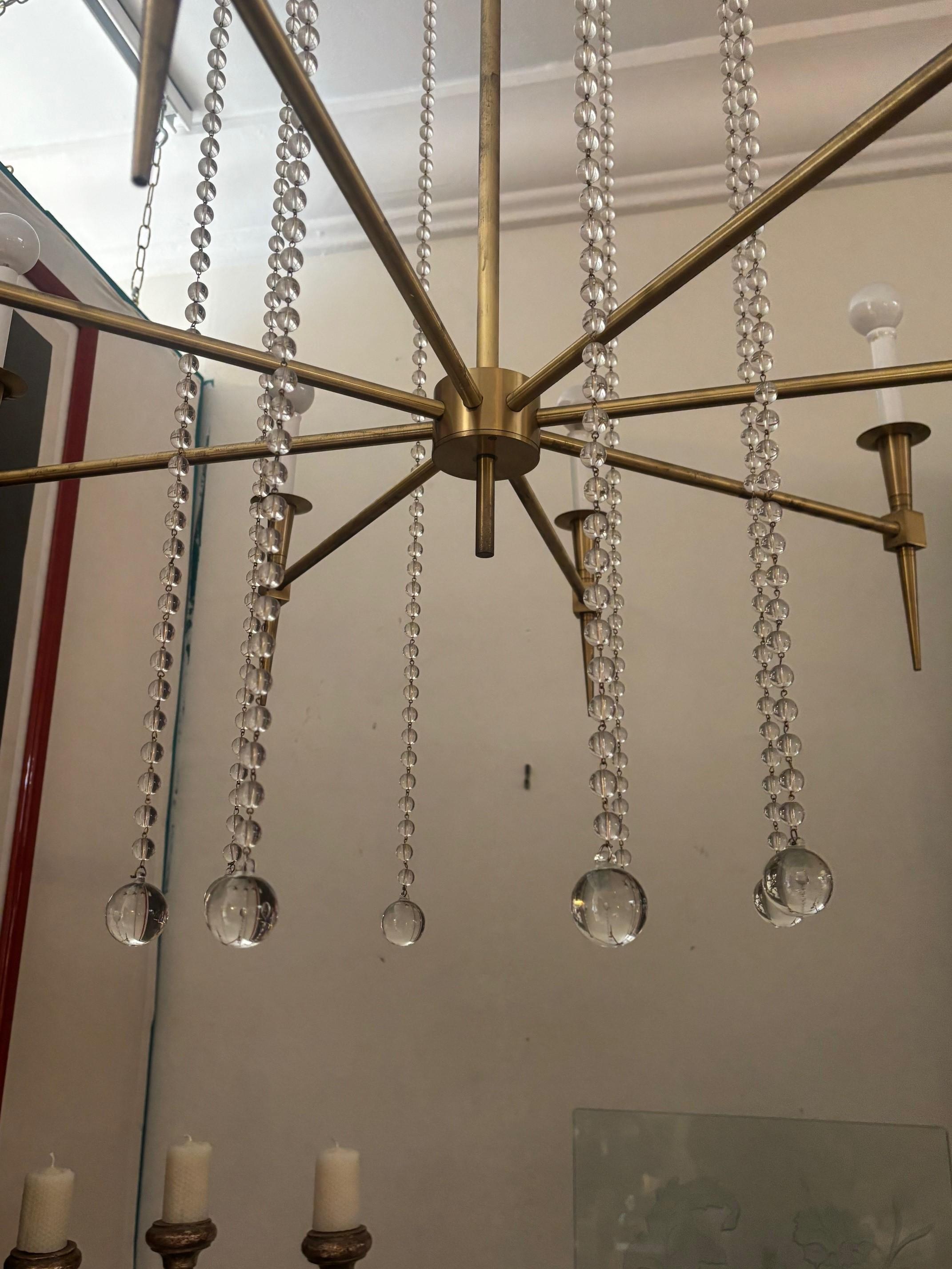 Un lustre très populaire en laiton poli et avec toutes les perles de verre suspendues. Fabriqué sur mesure pour un designer de Los Angeles, celui-ci est l'échantillon de la salle d'exposition. Réalisé d'après son dessin (Tommy Parzinger ) . 8 lampes