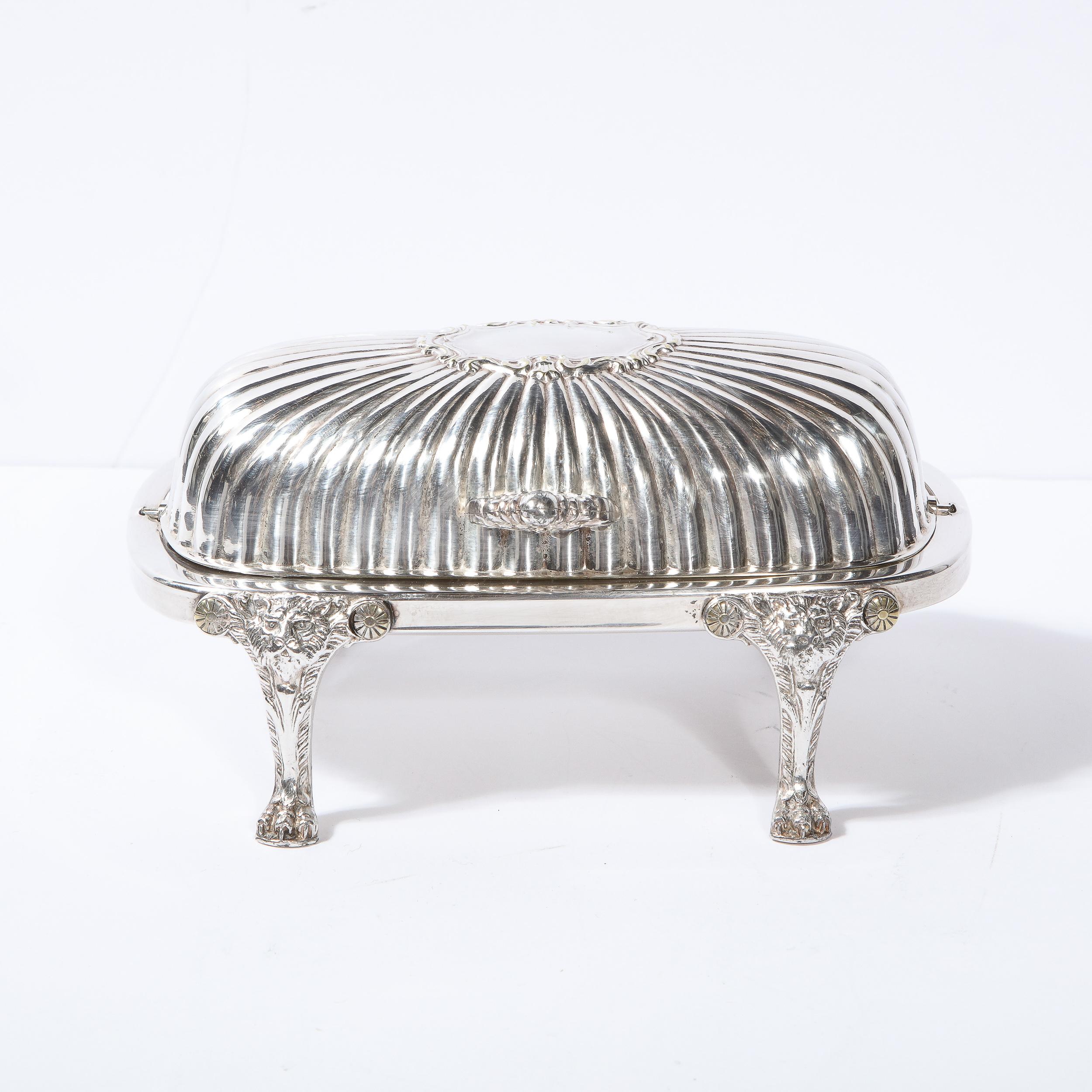 This elegant Mid-Century Modern silver plate butter dish was realized in the United States, circa 1950. It offers four claw form feat with stylized lions at their apex; a rectangular body with rounded corners; a stylized acathus leaf pull; and a