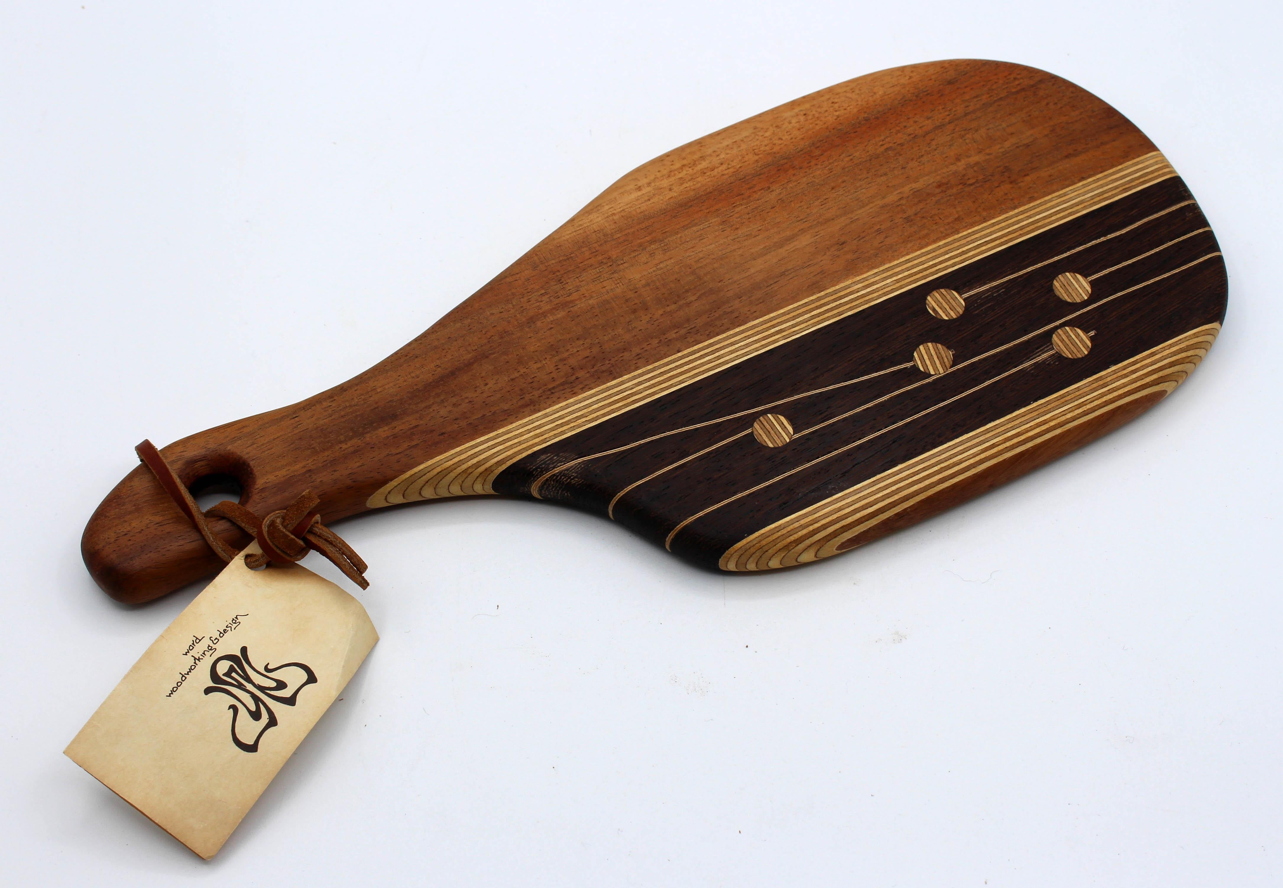 Circa 1970s cheese board by Stephen & Roseanna Ward, Newfane, VT. Retains original tag with all woods used including a hand notation of boxwood from England. They closed in 1984 after 38 years. 15 1/4