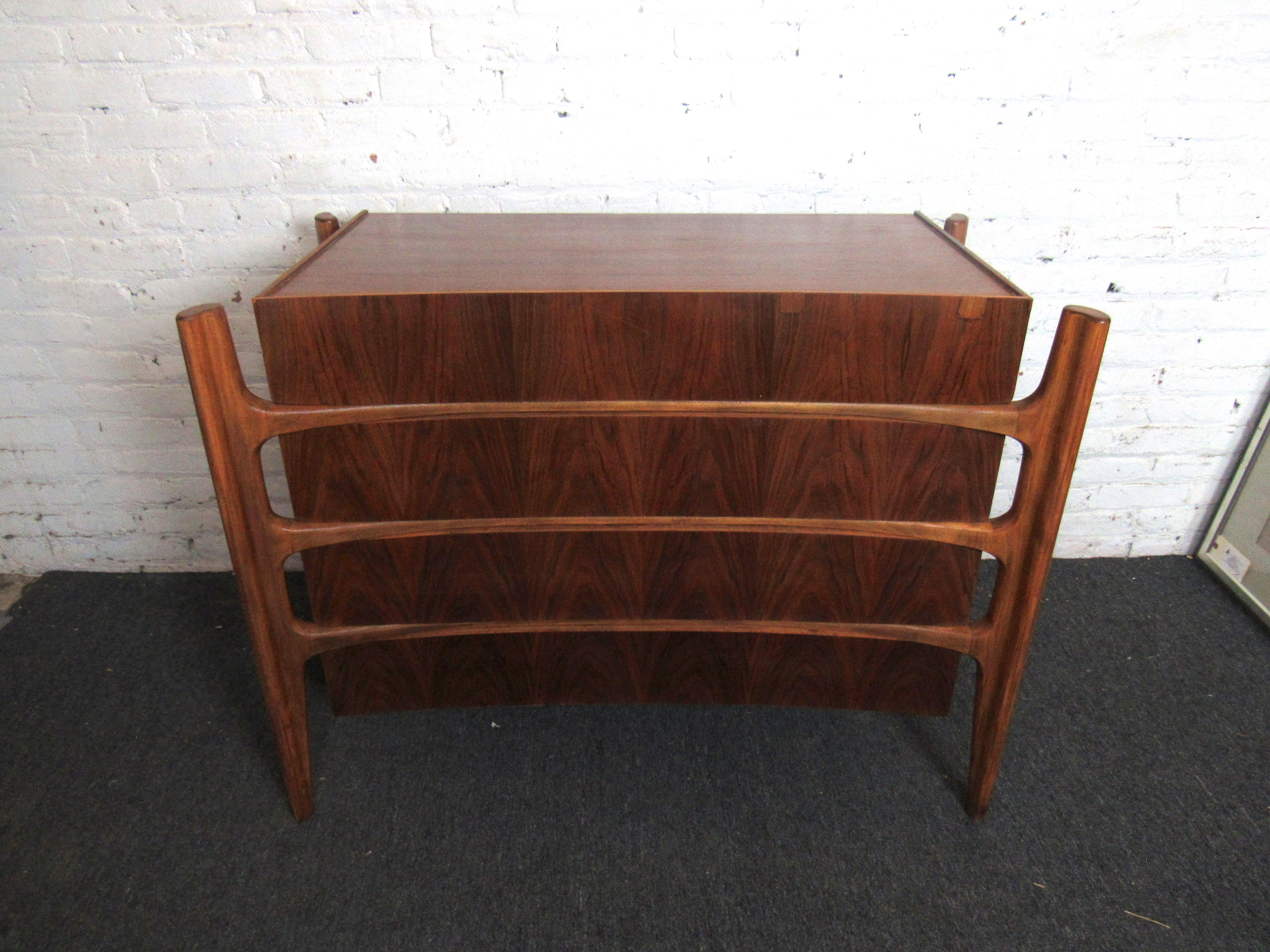 This chest of drawers in the style of William Hinn combines handsome walnut woodgrain with a unique design. Full of timeless Mid-Century Modern elegance and sturdy craftsmanship, this piece is both impressive and practical. Please confirm item