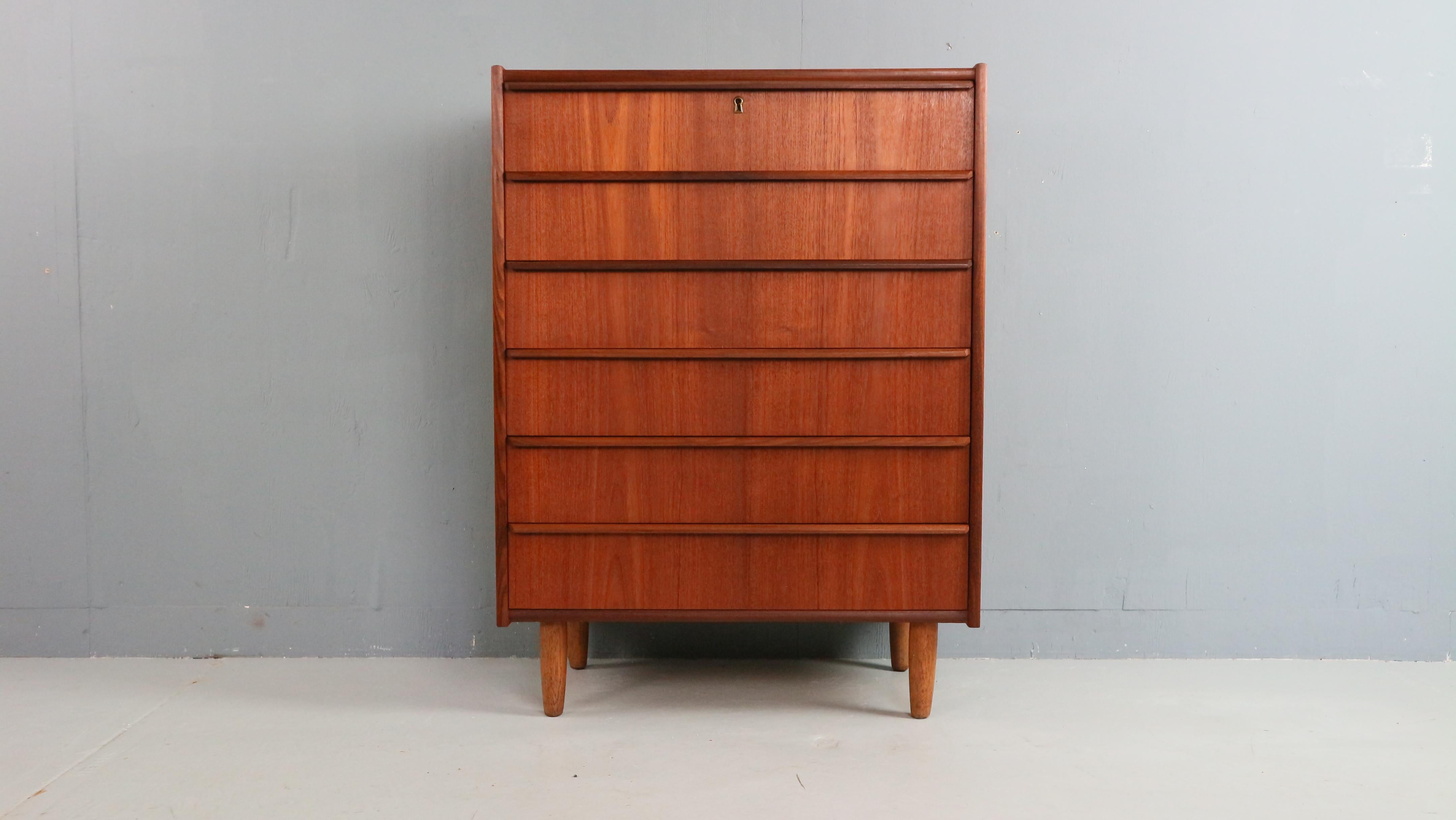 Eleganza della cassettiera tallboy proveniente dalla Danimarca, risalente agli anni '60. Realizzato in caldo teak, questo raffinato mobile presenta sei cassetti con maniglie integrate lungo il bordo superiore, segno distintivo dell'understated