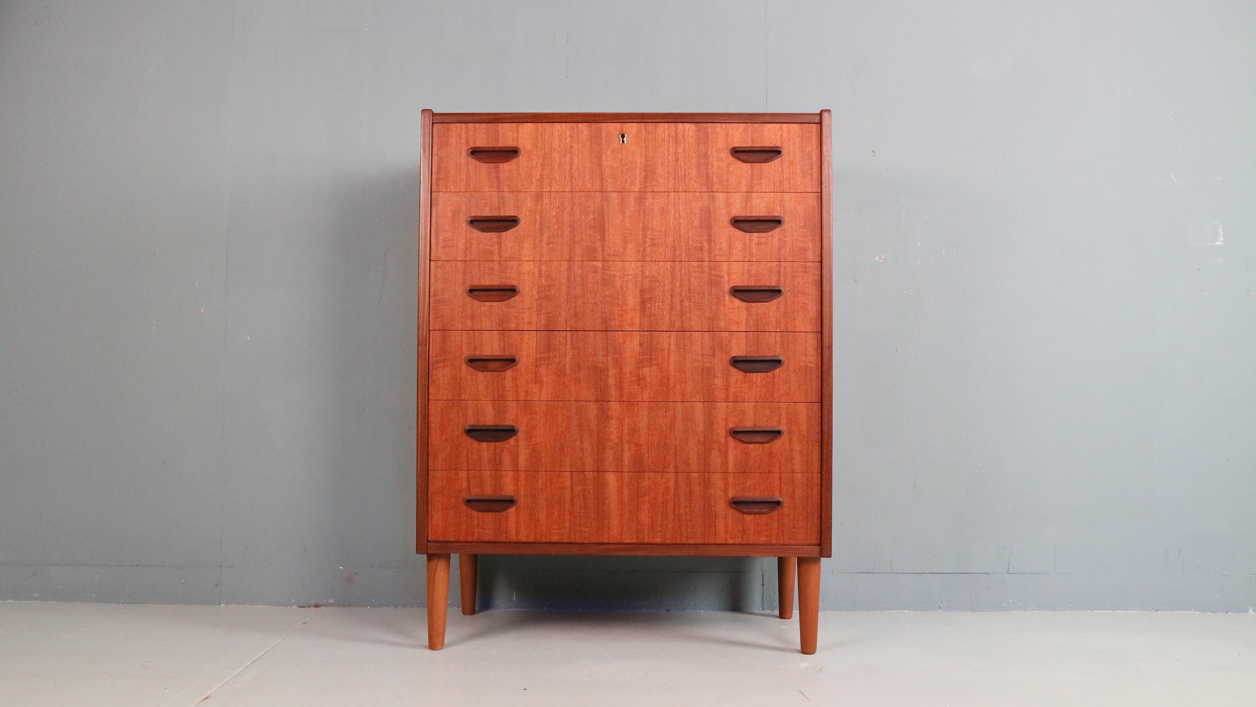Alta cassettiera danese degli anni '60, realizzata in caldo teak. Dispone di sei cassetti di dimensioni generose con maniglie incassate integrate, che contribuiscono al suo design elegante e sobrio. Un bellissimo esempio di modernismo scandinavo,