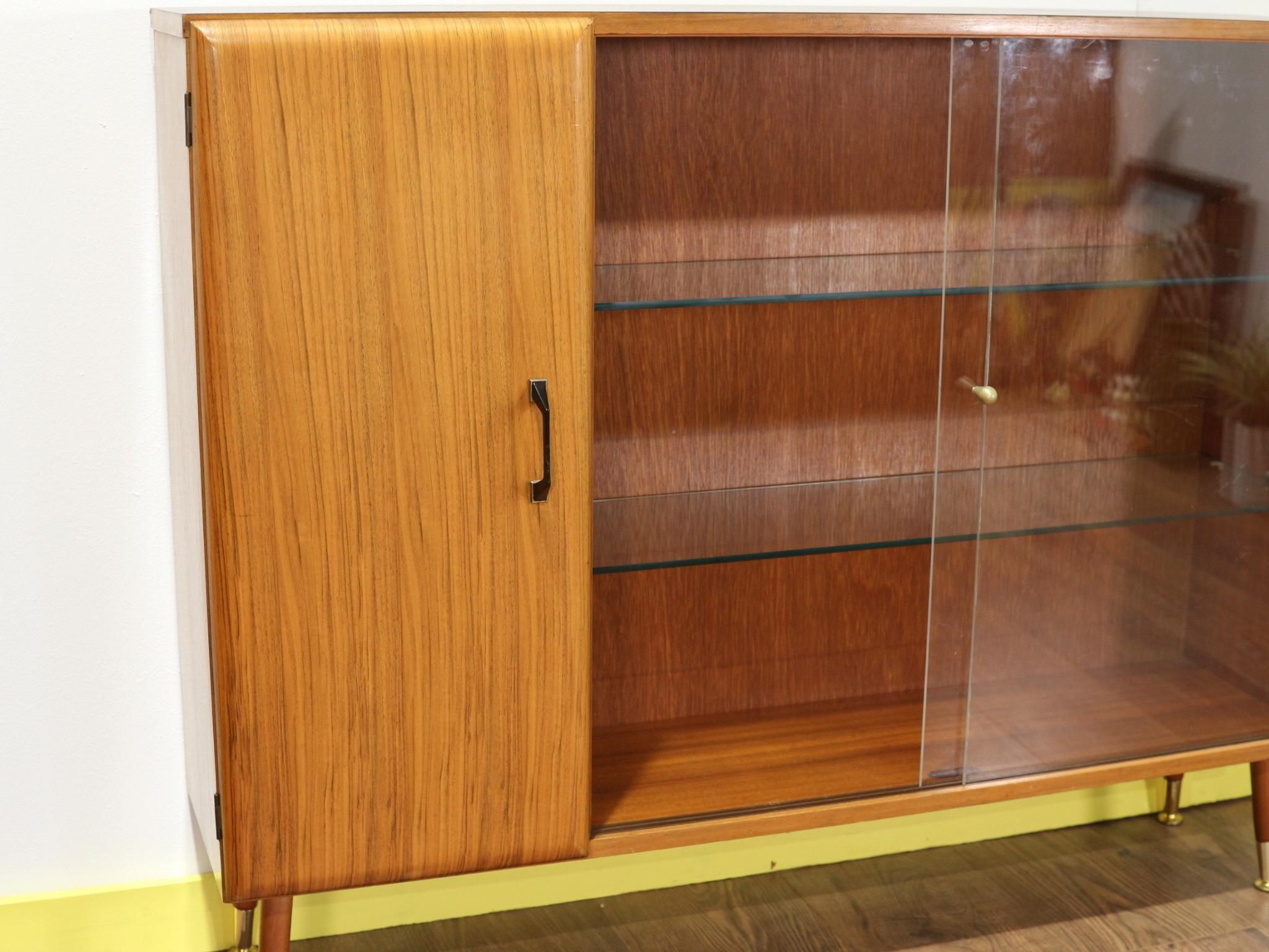 A beautiful mid-century china display cabinet made by Turnbridge of London. This gorgeous cabinet sat on atomic legs is a real head turner. With sliding doors and glass shelves there is plenty of display space