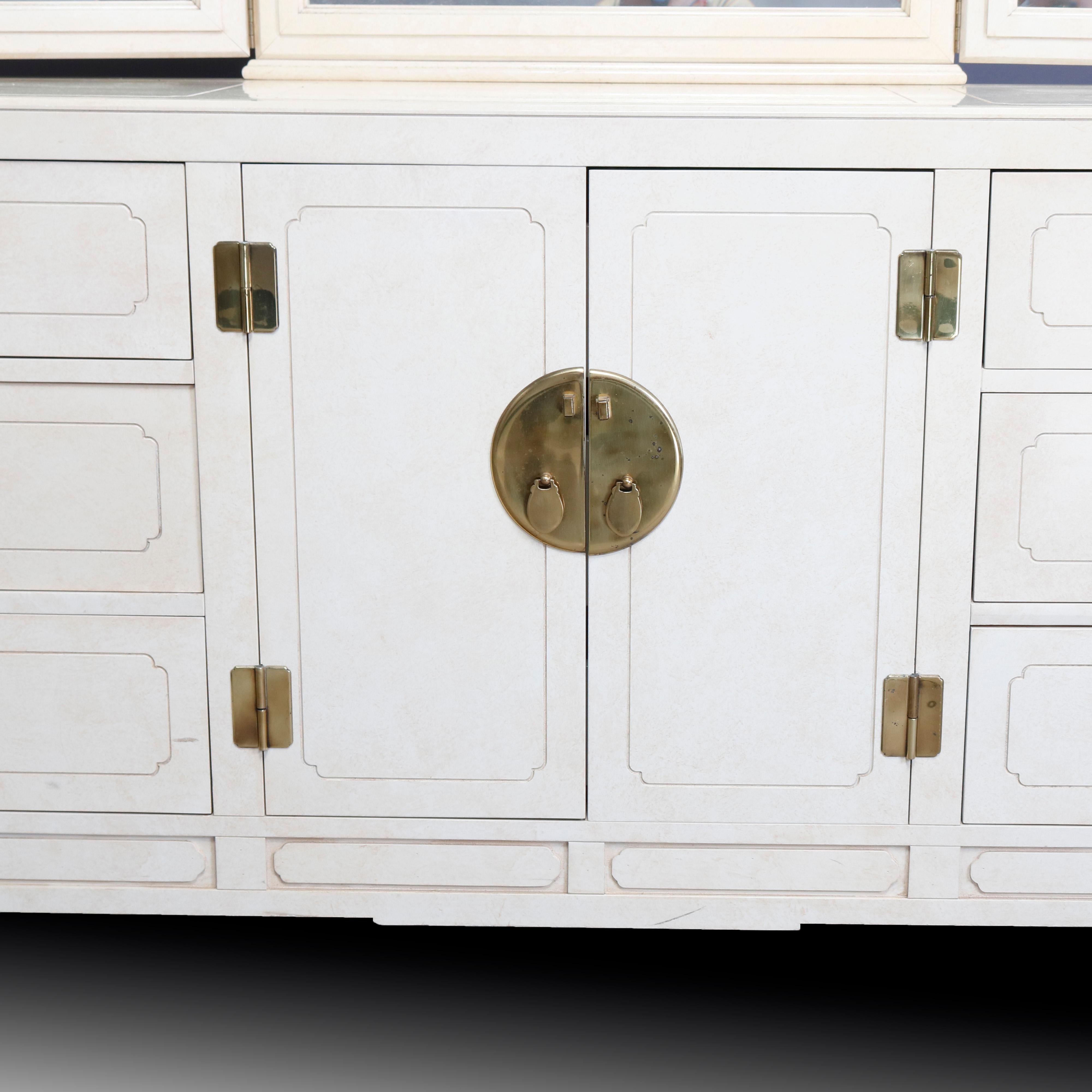 A Mid-Century Modern dresser by Hickory white offers Chinese Chippendale styling with all-over ivory enameled finish, pierced corbels having Asian influence, and cast brass hardware and accoutrements. Case with adjustable triptych mirror surmounting