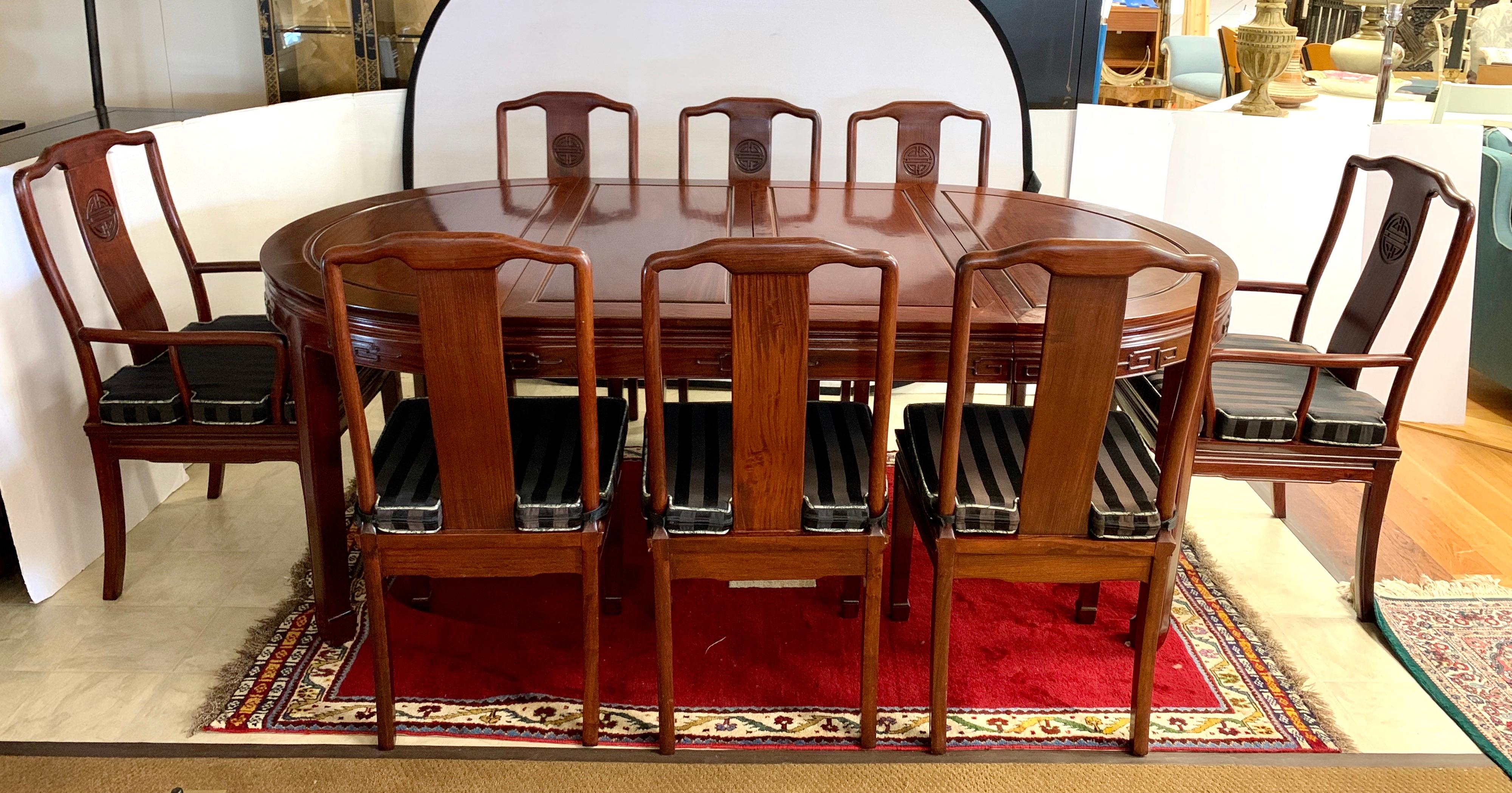 Asian Mid-Century Modern chinoiserie rosewood dining room set with table, two leaves and eight chairs with matching custom seat pads. Each of the leaves measures eighteen inches wide and there are two in total. The table expands from 46