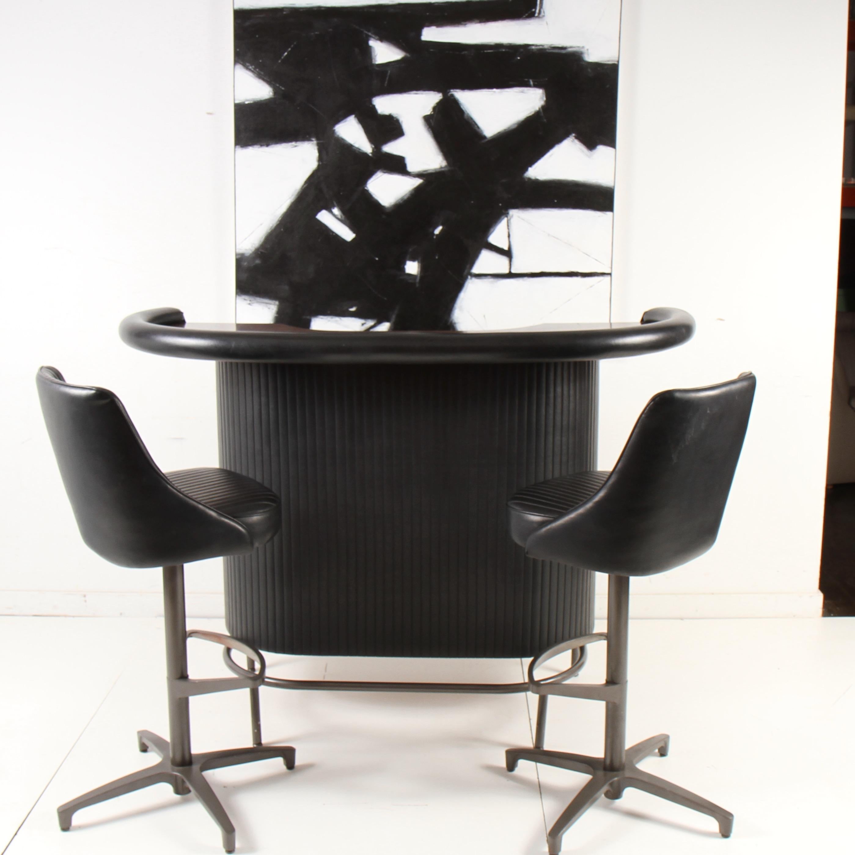 1970s era bar and stool set from Chromcraft, a maker of many iconic 1960s-1970s seating and accessory pieces. Clean black Naugahyde and wood toned formica bar with gunmetal painted footrest, with matching pair of barstools. Bar measures: 61.5