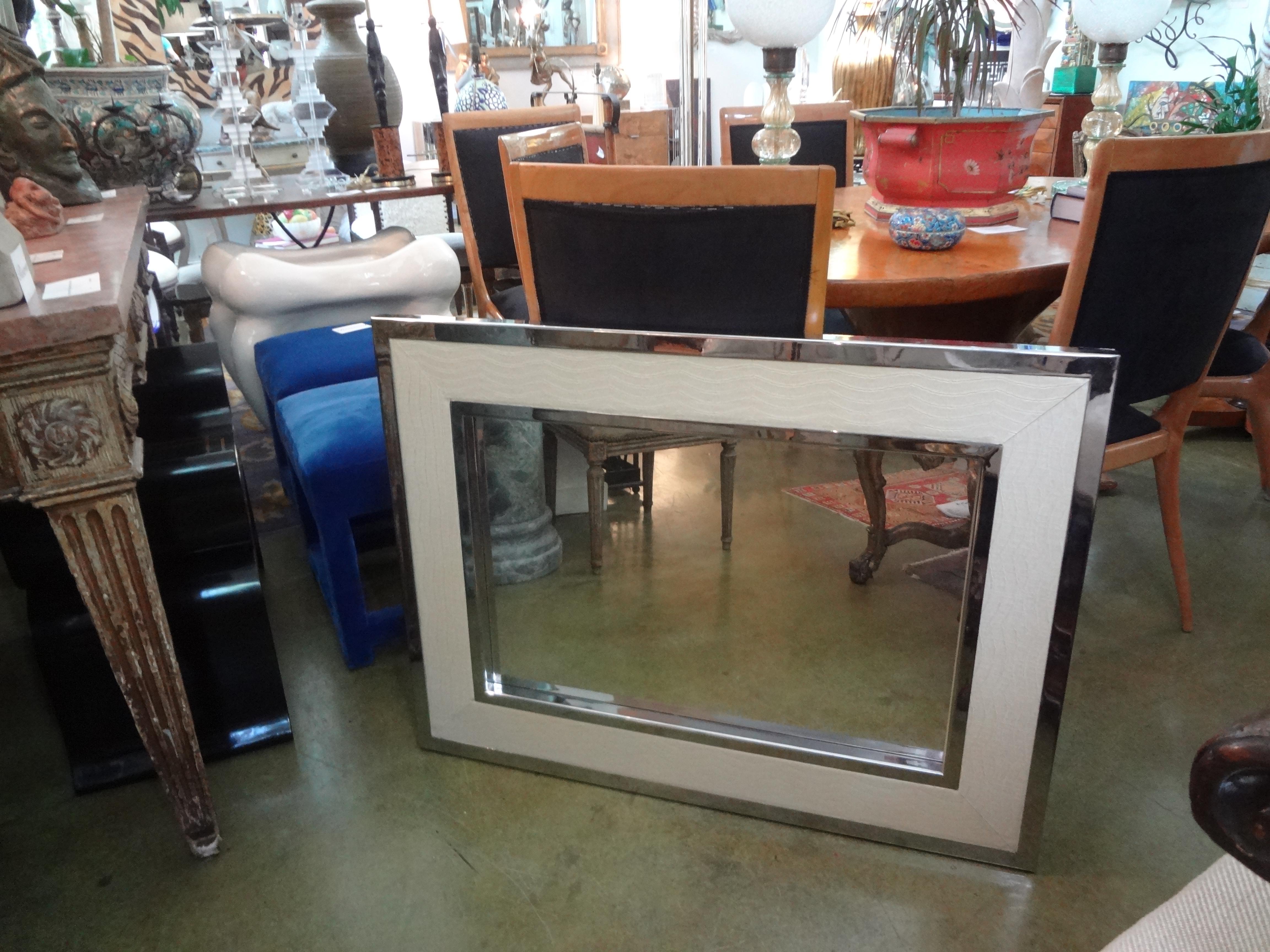 Stunning Mid-Century Modern Milo Baughman style chrome and faux alligator mirror. This beautiful Hollywood Regency mirror has a double chrome frame inset with cream colored faux alligator. Our versatile well made midcentury postmodern mirror is