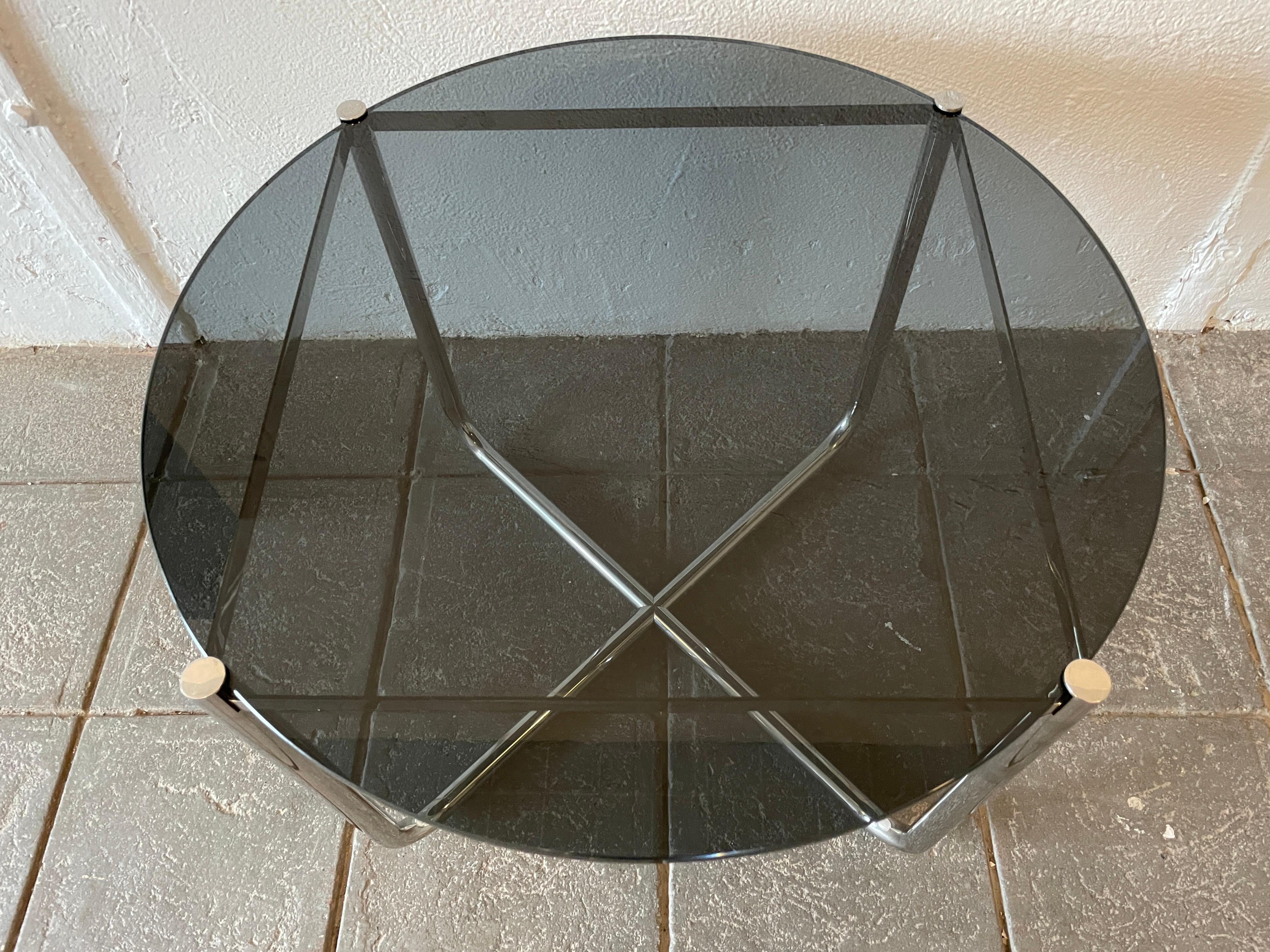 Beautiful heavy chromed round side table featuring a thick tinted glass top and bent tube frame. The top can be removed from the frame for easier moving. The dia. is 20 inches and the height is 22 inches. Showing very little use.

Glass is tinted