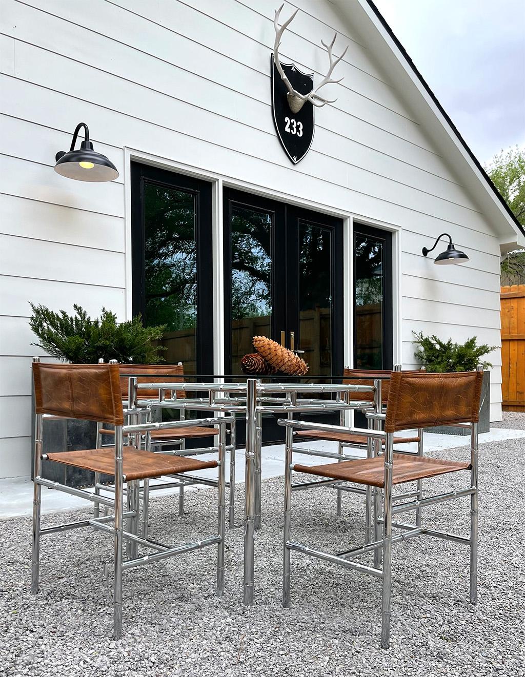 Incredible Mid-Century Modern, Hollywood Regency dining set with a square glass top table and four chairs. The frames of the table and chairs are made of a chrome metal faux bamboo. The seats and backrests of the chairs are a saddle colored faux