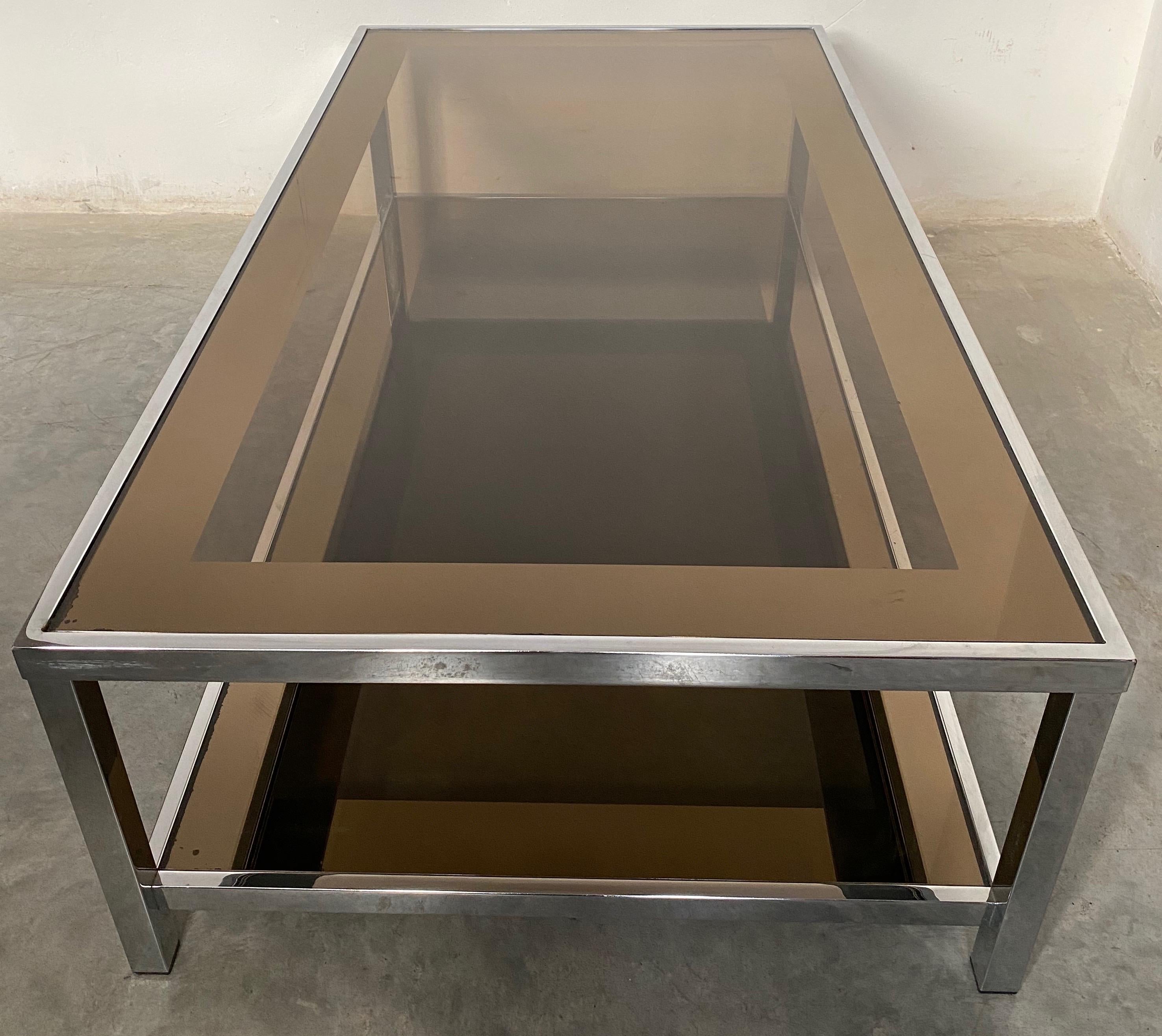 Belgo Chrome was well known for its handsome clean designs in metals and mirror. This 1980s coffee table is iconic of their designs. The 2 smoked glass tops are smoked glass and have a mirrored bronze border 7 cm wide. The border further emphasizes