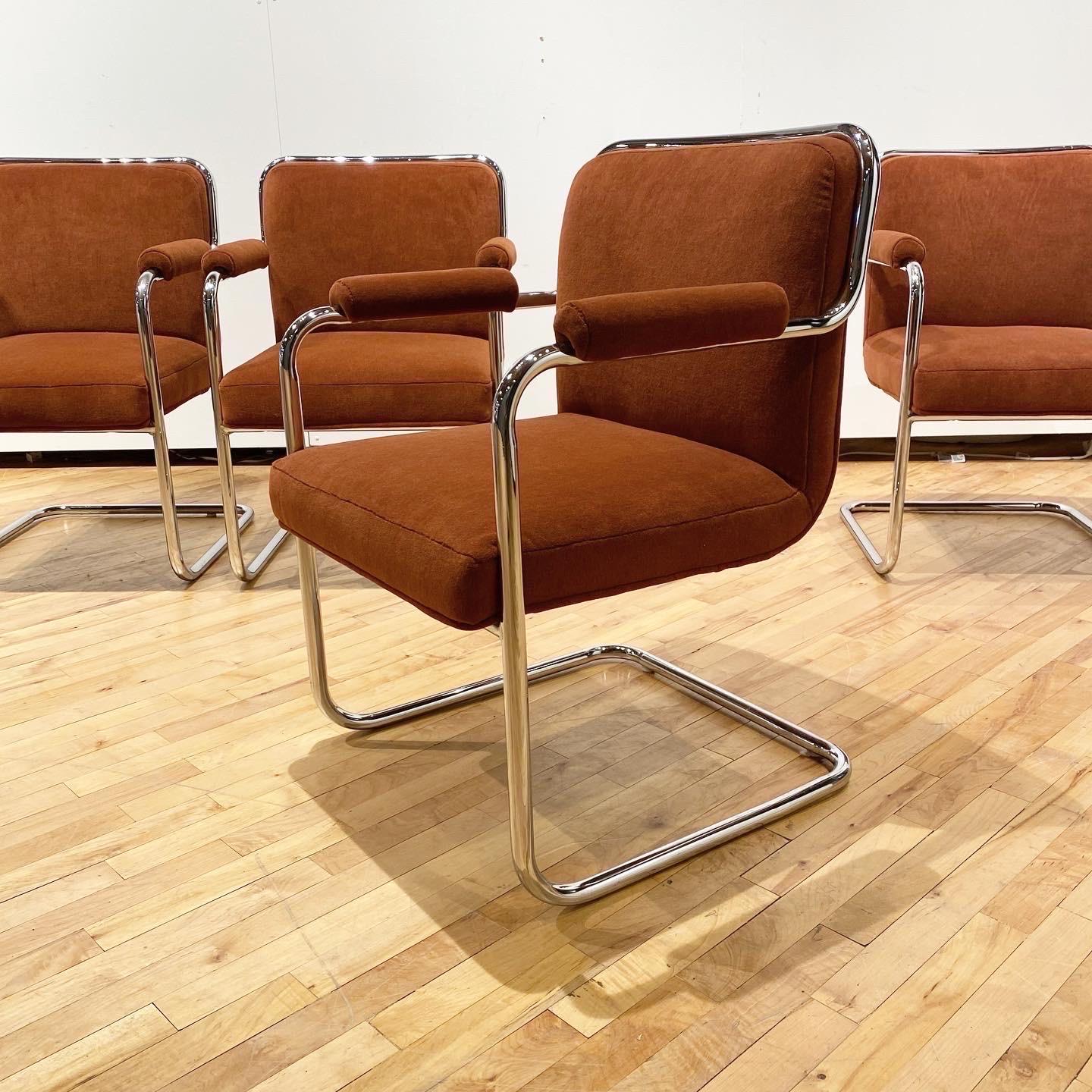 A classic set of cantilevered armchairs in the style of Marcel Breuer and Mies Van Der Rohe. These have a wrap around tube frame with newly upholstered seat and back. The rust colored velvet is sturdy and soft and a wonderful contrast to the chrome