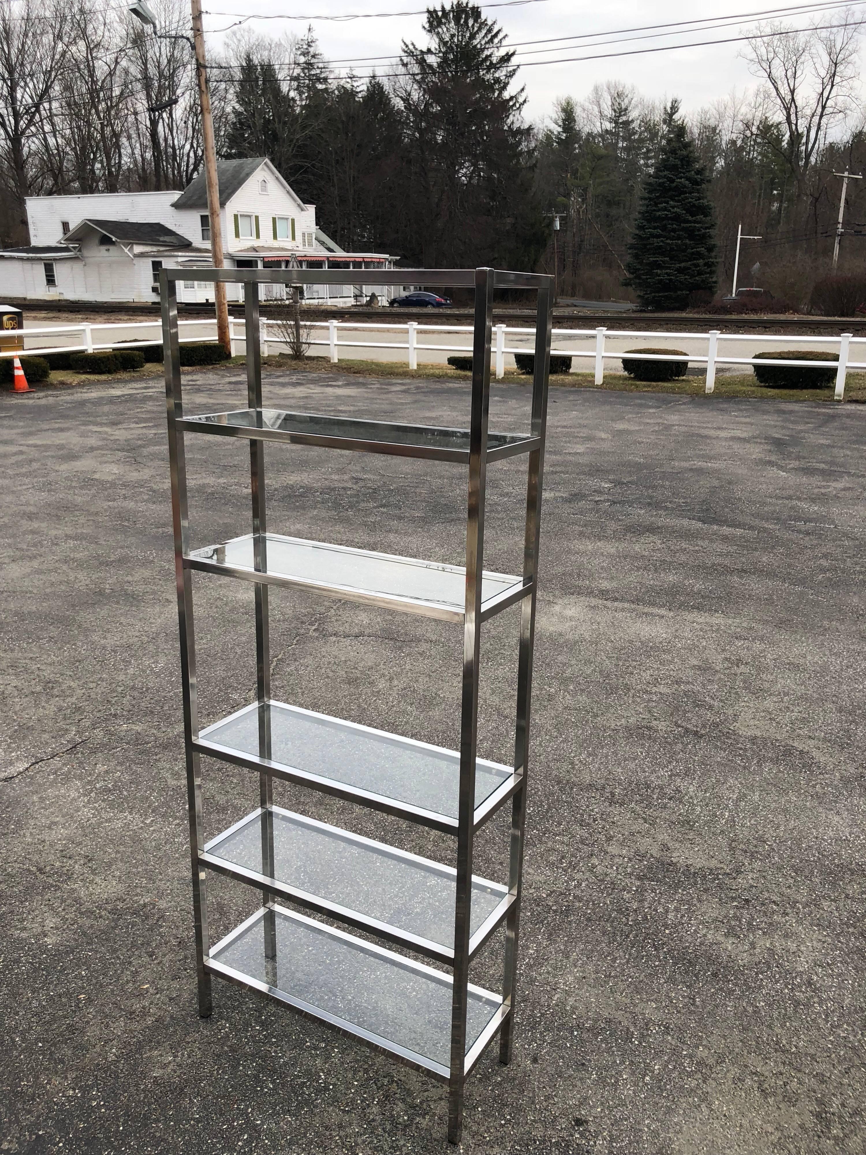 Mid-Century Modern chrome étagère with five glass shelves. Minimalist look but great storage. Clean ,sophisticated lines make this a classic for all designs. Space between each shelf is 12 inches except for the center shelf is 18 inches. 