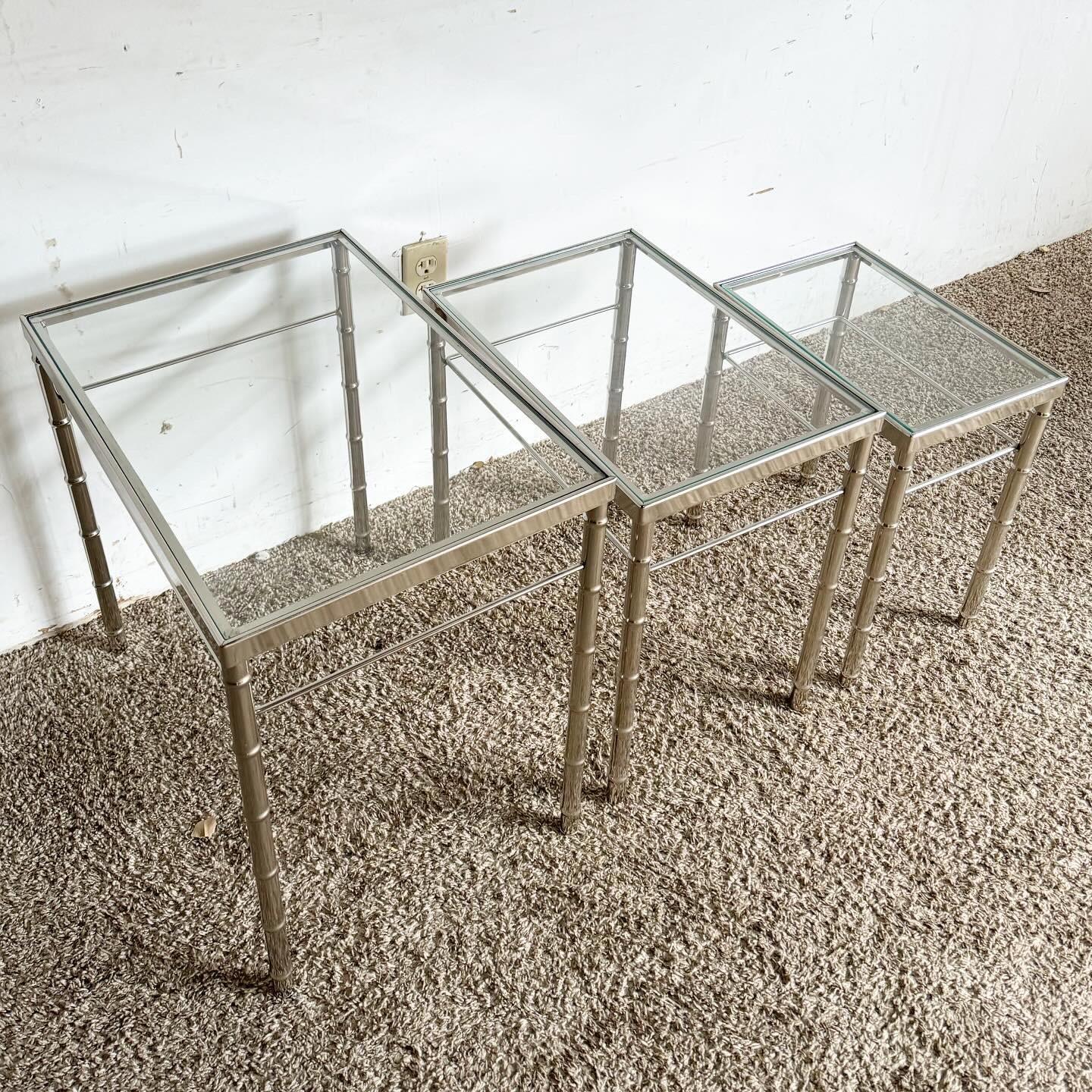 Discover the versatility and style of the Mid Century Modern Chrome Faux Bamboo Glass Top Nesting Tables, a set of three. Featuring chrome frames with a bamboo-like design and clear glass tops, these tables offer a blend of mid-century charm and