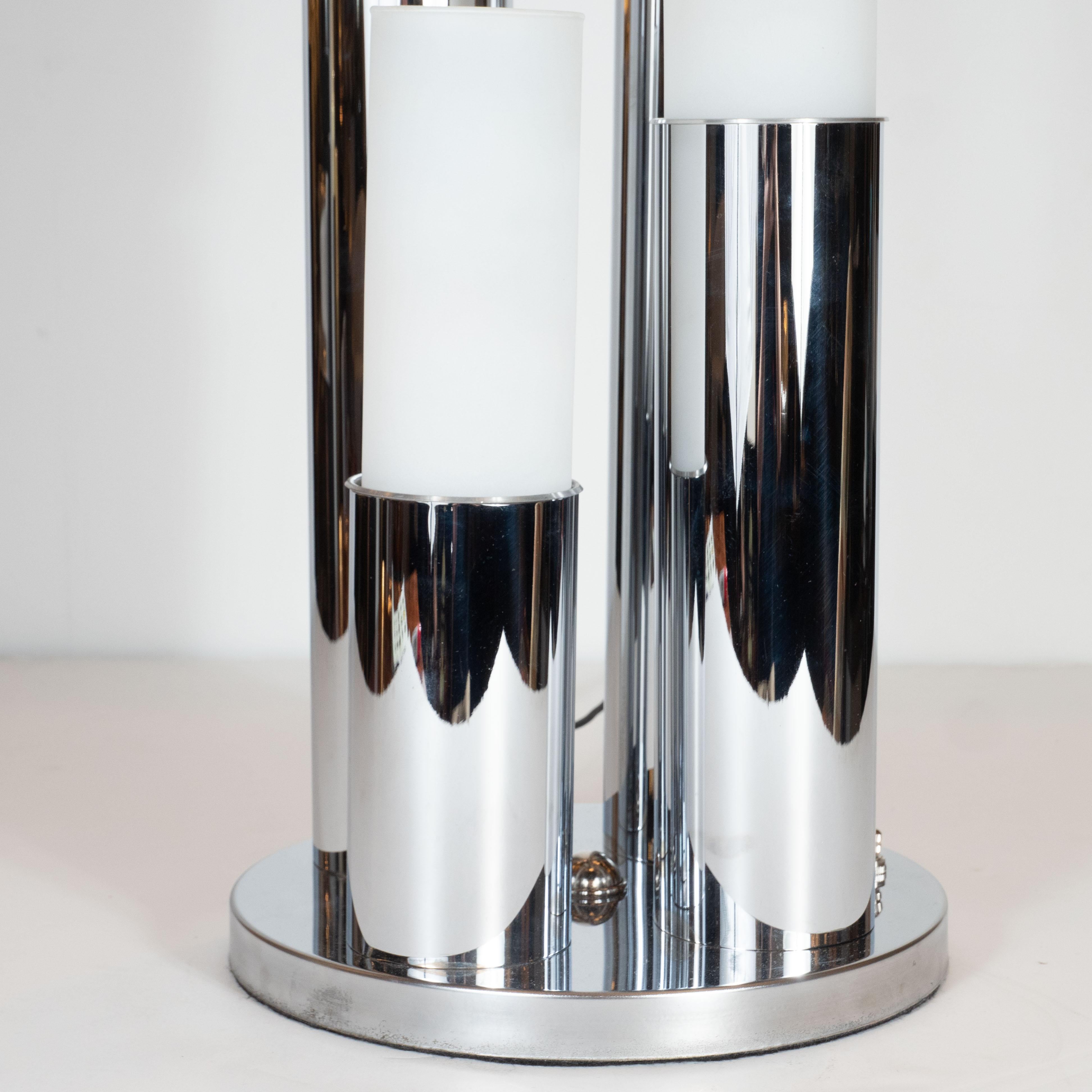 This stunning and graphic Mid-Century Modern uplight/ table lamp was realized in the United States, circa 1970. It features four cylindrical bodies rising from a circular chrome base, like perfectly formed stalagmites, capped with frosted glass