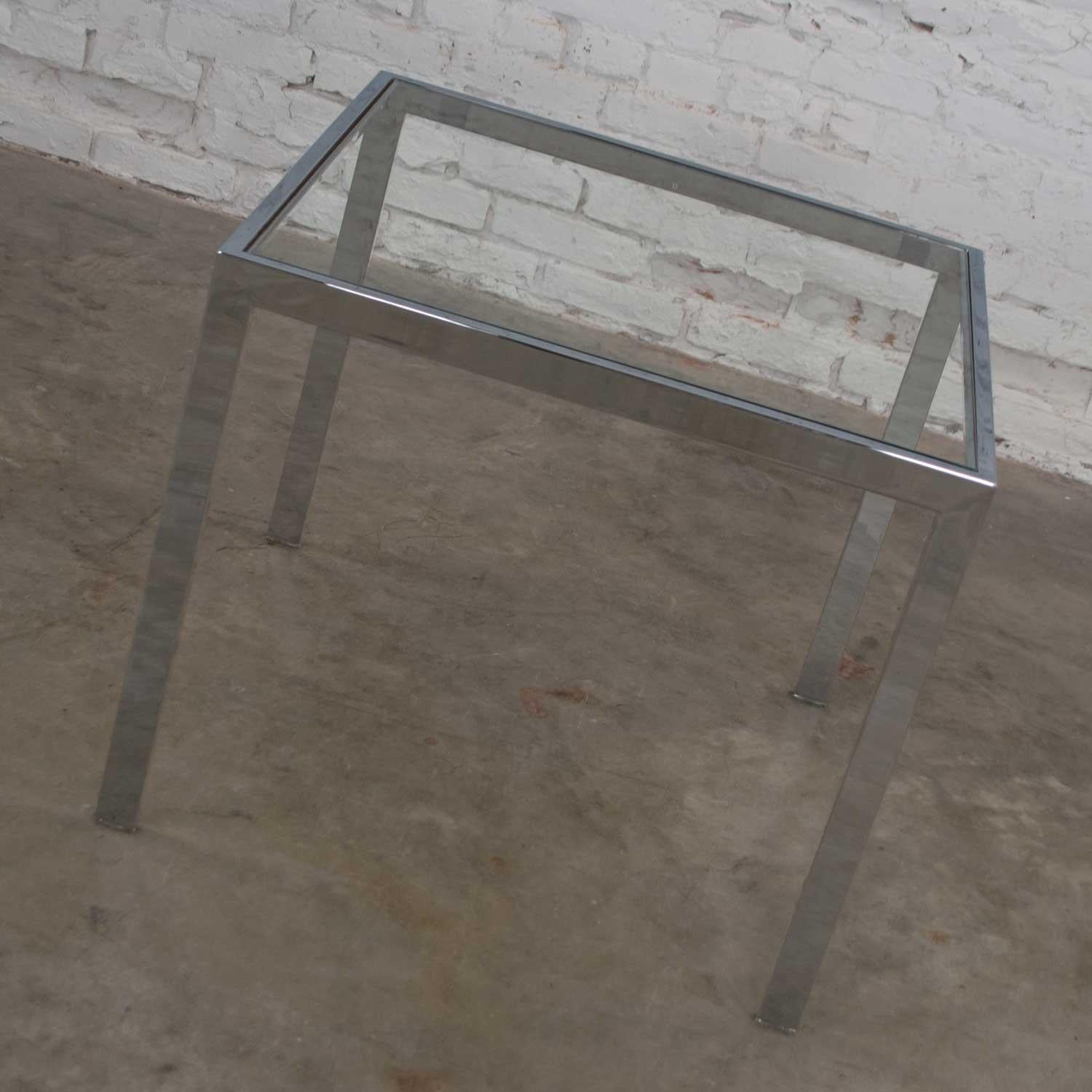 Handsome Mid-Century Modern chrome and glass square Parsons style end table or side table after similar designs of Milo Baughman. It is in wonderful vintage condition. The chrome tube frame does not show any outstanding flaws but there is a bit of
