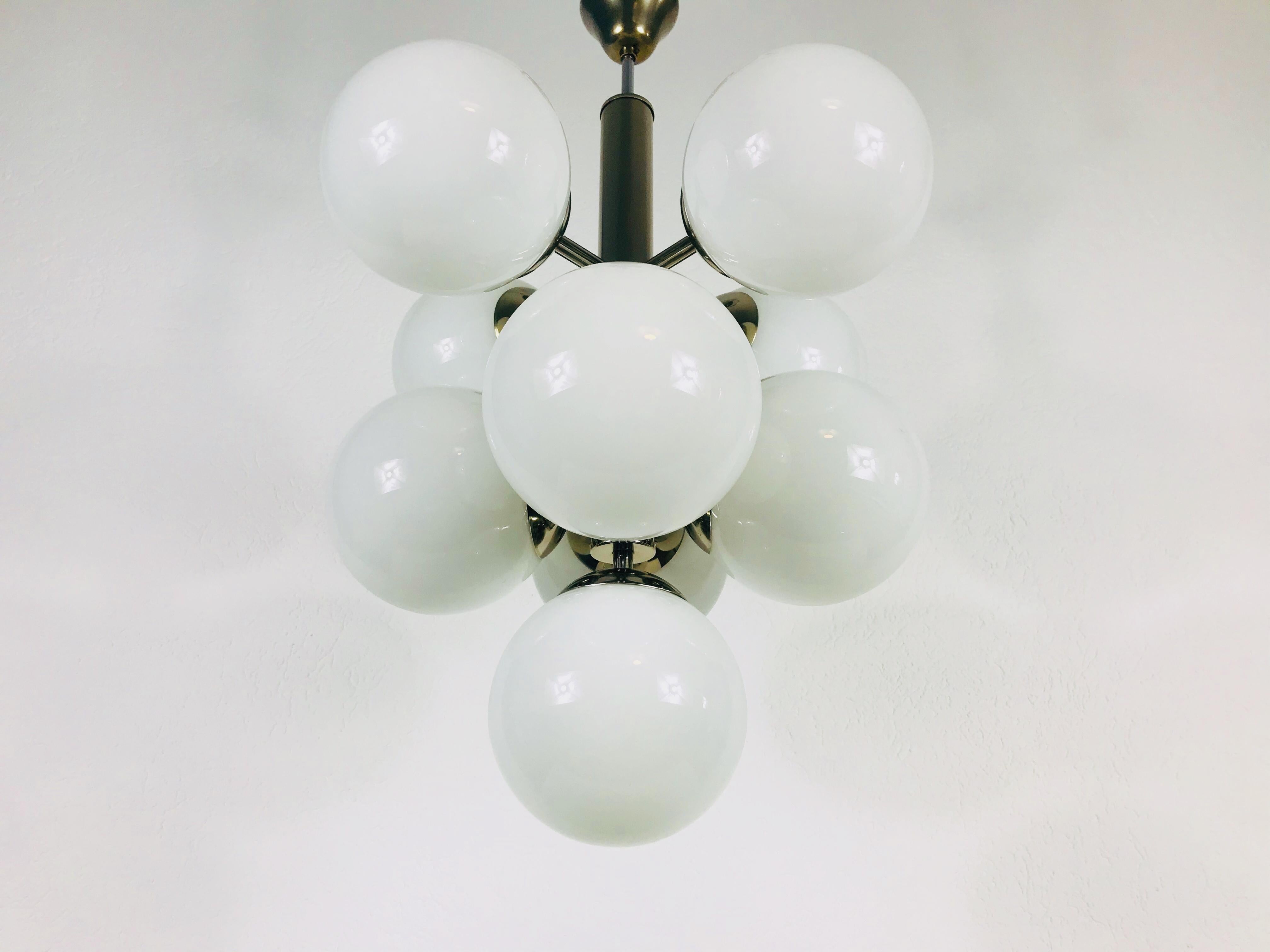 A midcentury chandelier made in Germany in the 1960s. It is fascinating with its Space Age design and nine opal glass balls. The body of the light is made of chrome metal, including the arms. 

The light requires nine E14 light bulbs.