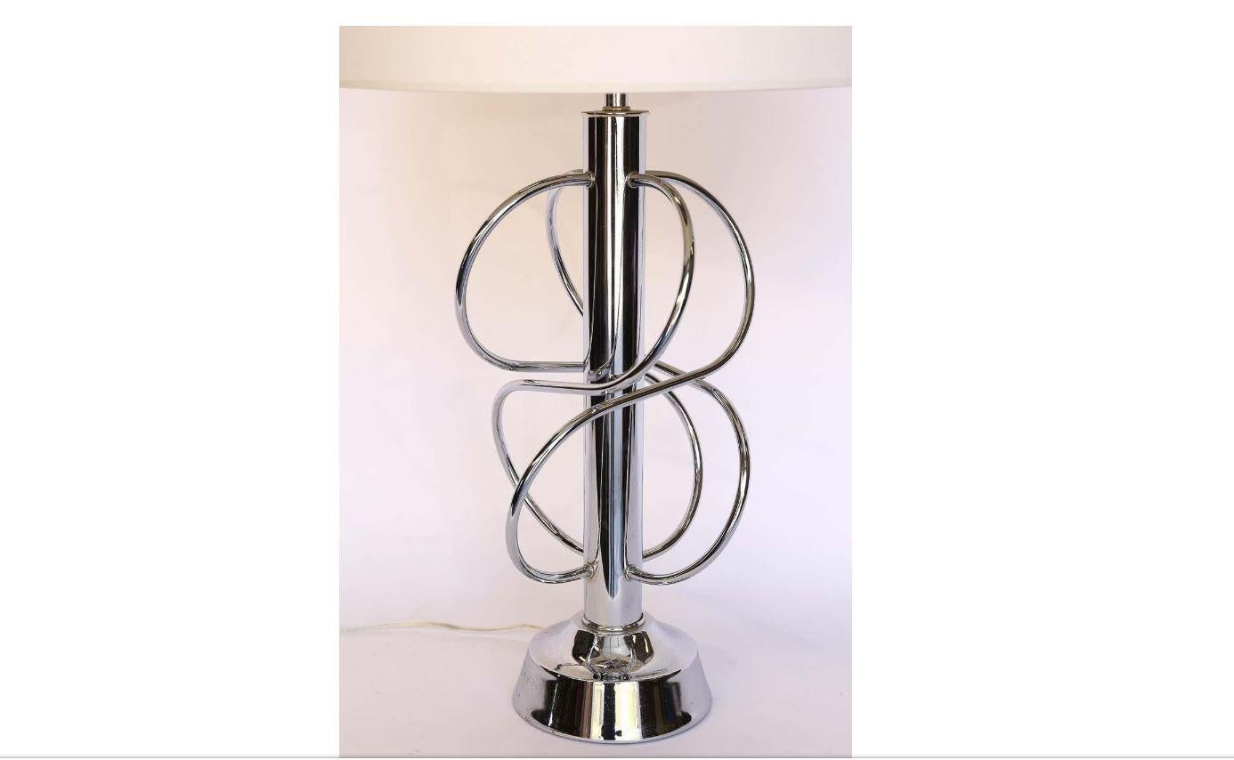 This is a chrome Mid-Century Modern table lamp with shade. The chrome twists and turns in a sculptural pattern. Newly wired and new shade included. The lamp measurements without the shade are 34 inches high and 11 inches in diameter. The shade