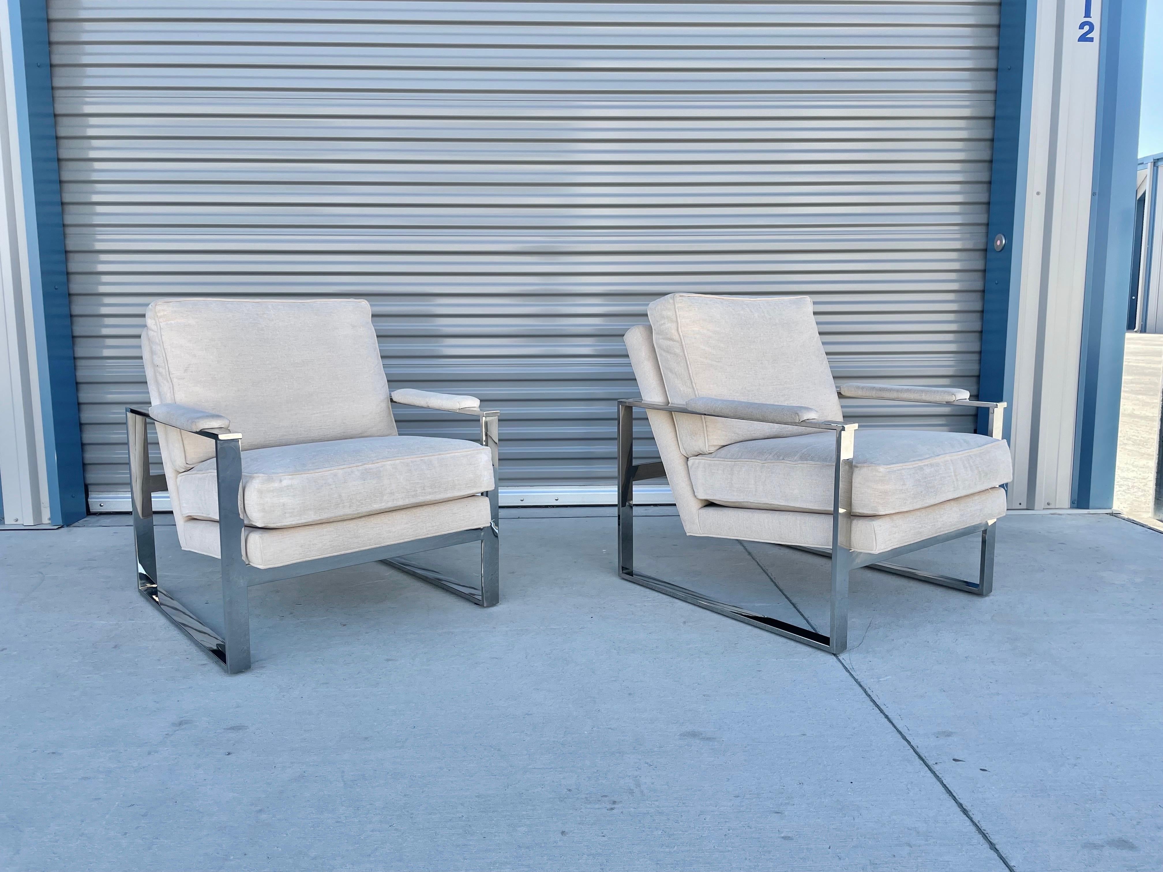 Midcentury chrome lounge chairs were designed by Milo Baughman for Thayer Coggin. These beautiful pair of chairs feature a heavy chrome base with a white upholstery that does have a bit of age to it but can be use as-is, or you can have them
