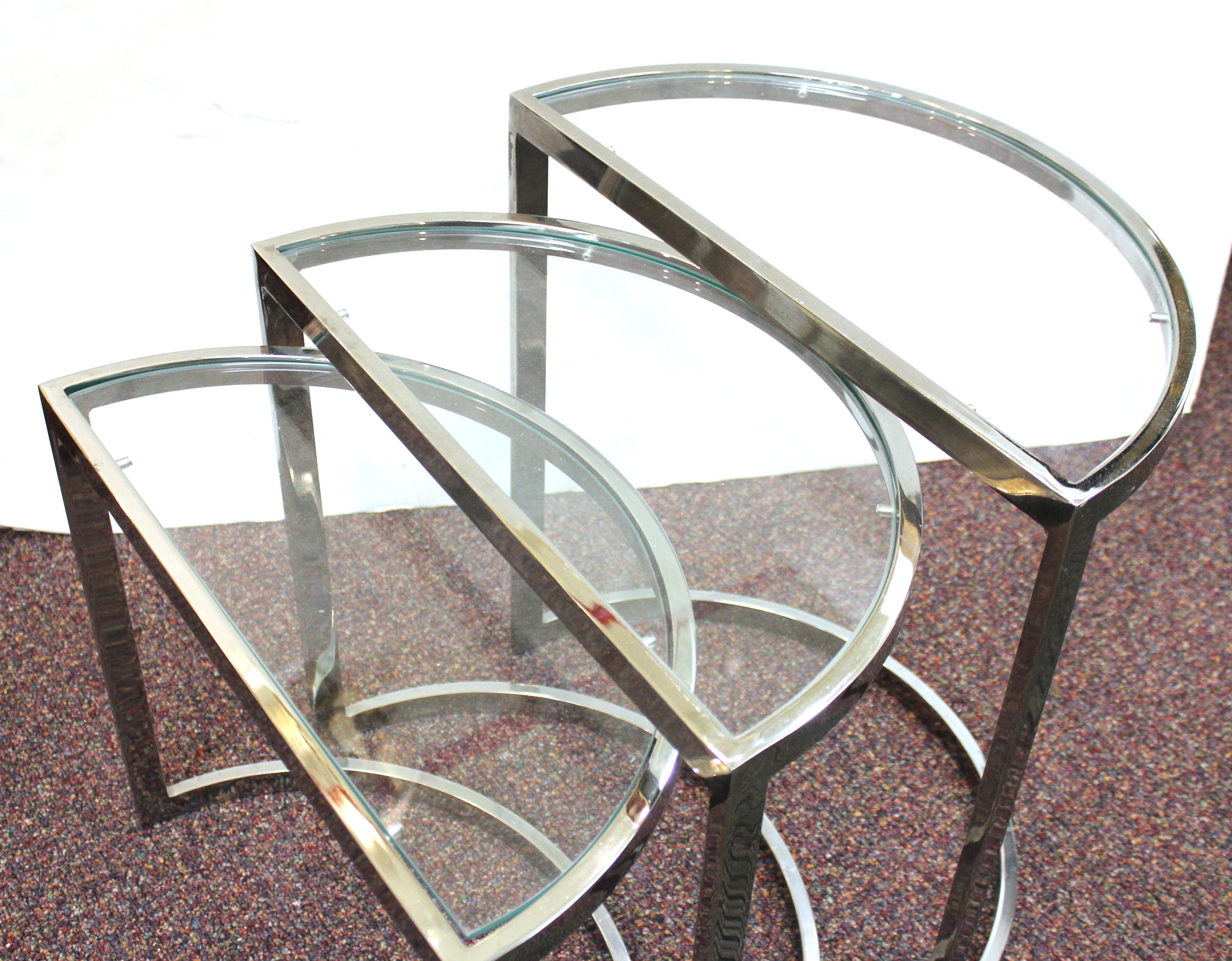 Set of three Mid-Century Modern chrome frame nesting tables in half-moon shapes with glass tops. Can fit into each other in various ways. Some minor scratches to the chrome finish, but overall in great vintage condition.