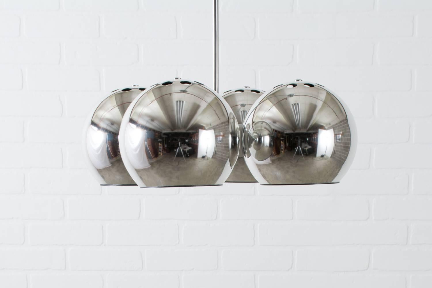 This vintage midcentury chrome pendant lamp features four chrome globes attached to a single chrome rod. Lightolier label on the ceiling plate.