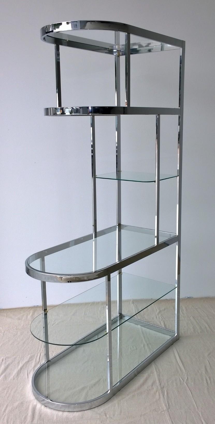 Offered is a Mid-Century Modern Design Institute America attributed chrome-plated metal and six glass shelves curved étagère with brass and rubber supports for the glass shelves. Would work great in a corner or space where the piece becomes a part