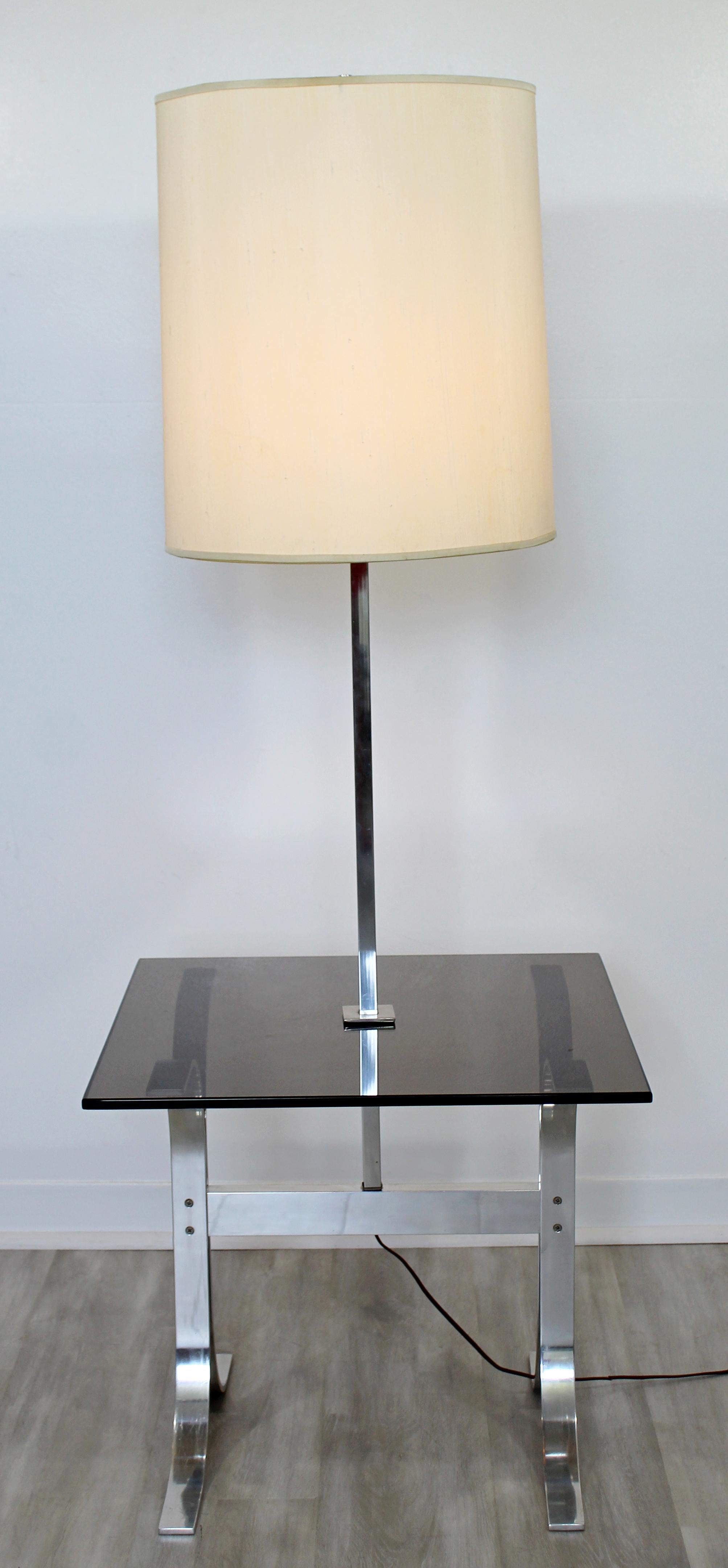 For your consideration is a gorgeous, chrome floor lamp, with a smoked glass table attached, circa 1970s. Includes original shade and finial. In very good vintage condition. The dimensions are 22