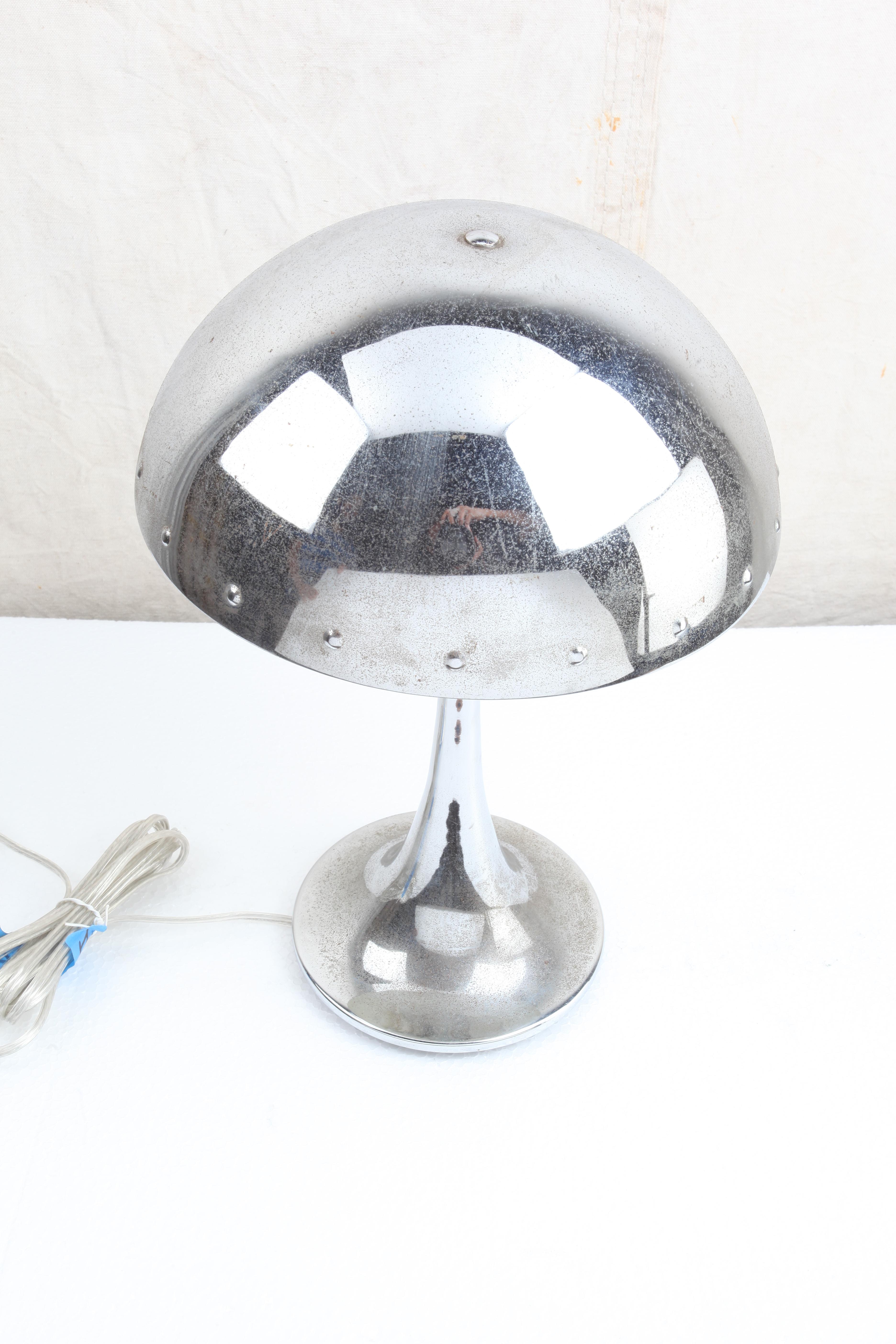 A mushroom-shaped chrome table lamp with rivets along the edge of the shade. Nice tapered base. Takes a standard base light bulb. European but rewired for American use.