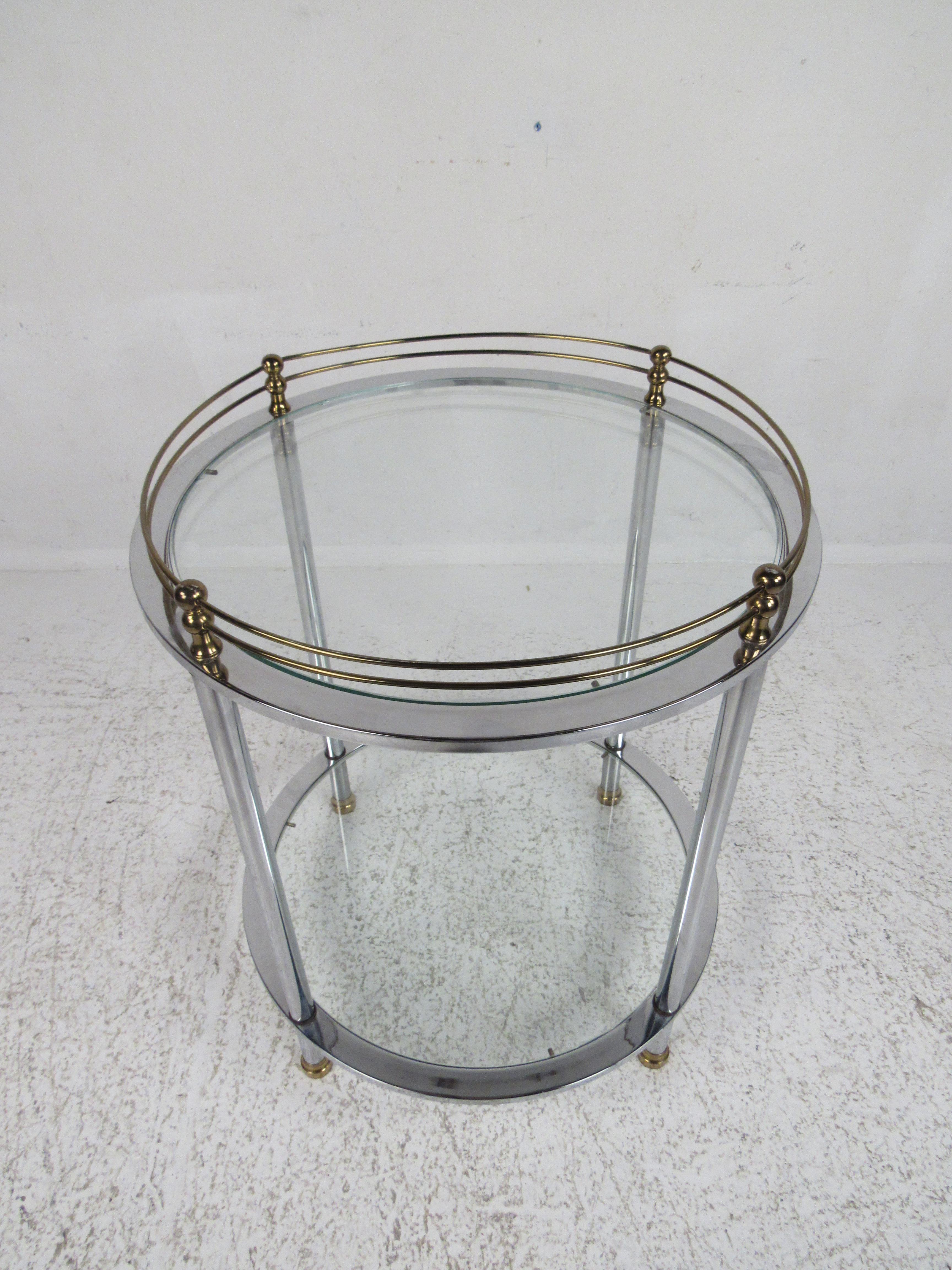 This stylish vintage modern side table features two tiers with glass inserts and a chrome frame. Brass fixtures support thin bent rods that wrap around the top. The unusual round shape allows this end table to fit into any setting. The circular