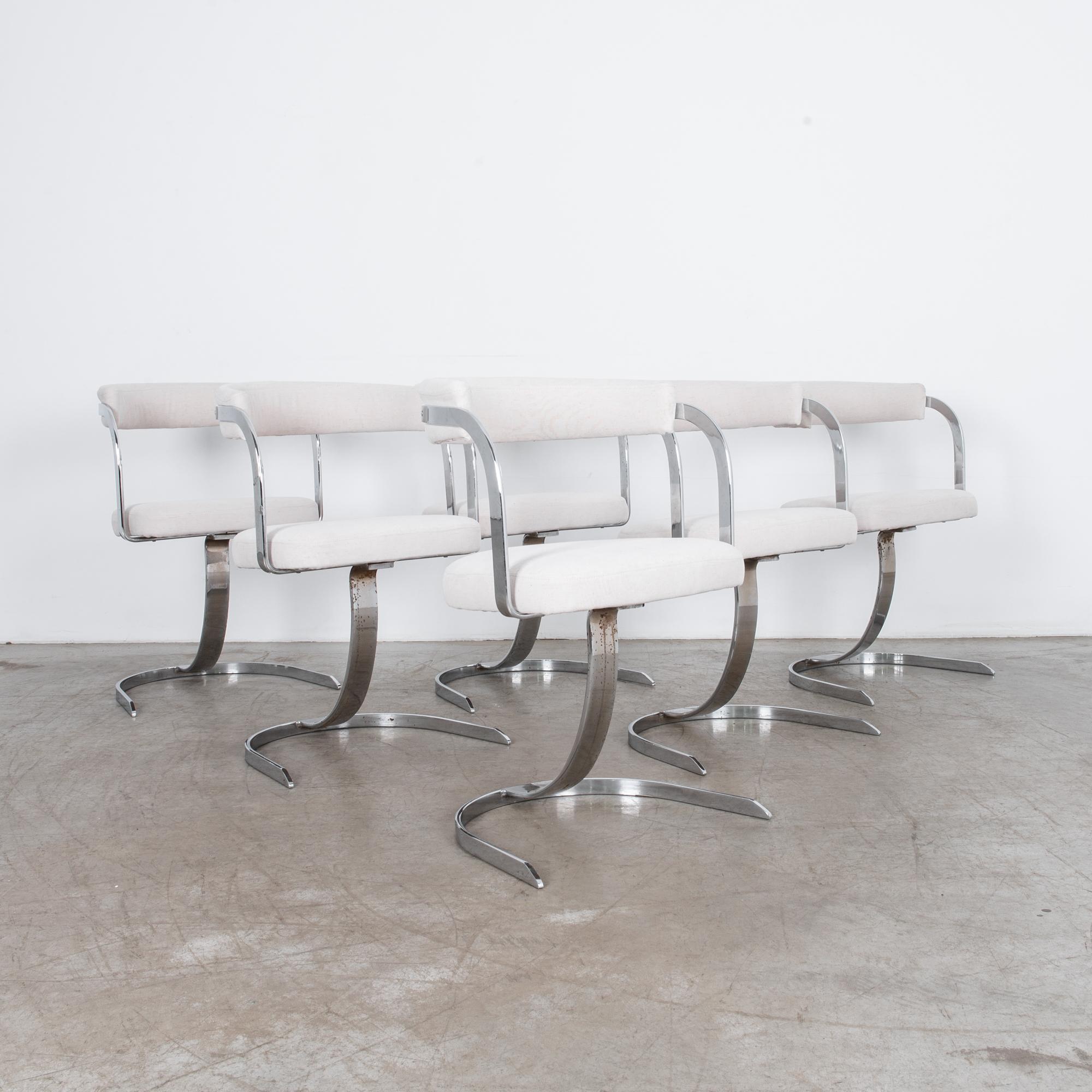 Counter-height armchairs, with tall single cantilevered leg. From France, circa 1960. Unique form in chrome plated steel, with striking geometric arms. Organic geometries are multiplied by this complete set of six. Comfortable seat and back cushions