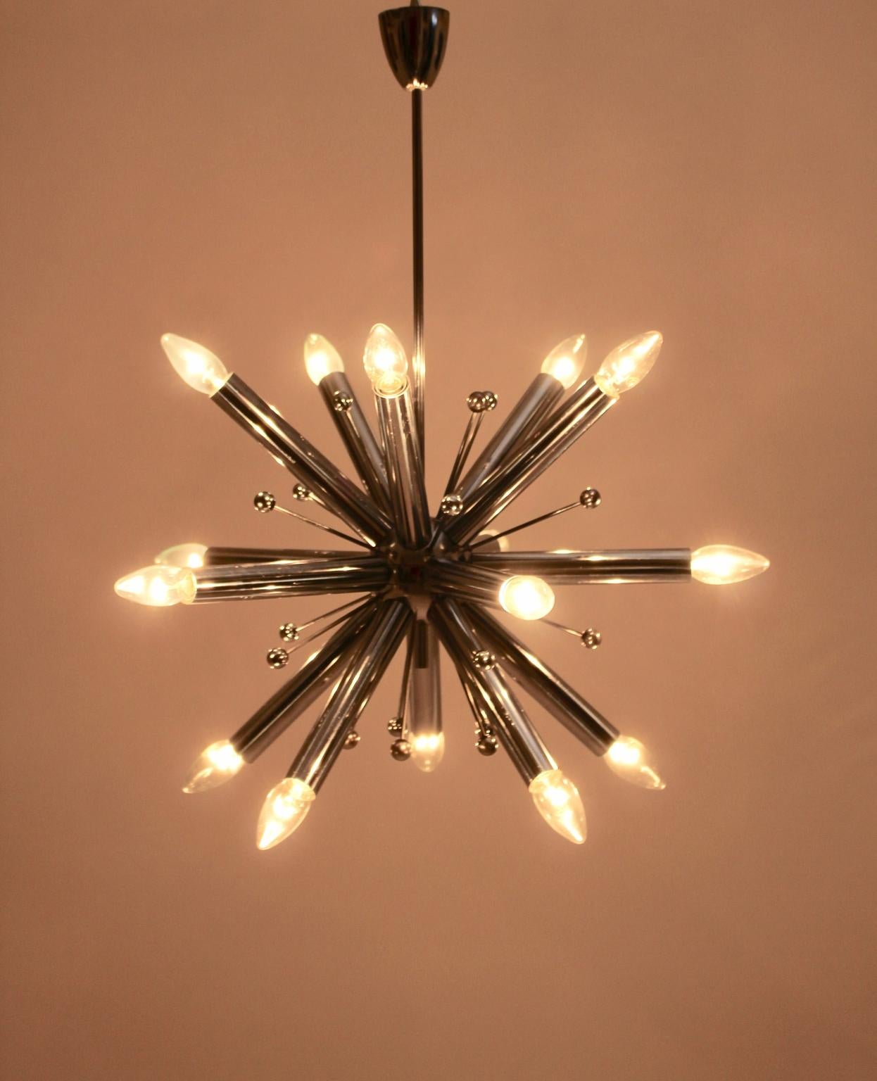 This presented Mid-Century Modern chandelier was designed and executed, circa 1960.
Also the chandelier shows 15 sockets E 14.
Furthermore the hanging lamp features a great size with approx. 63 cm diameter.
The vintage condition is very good with