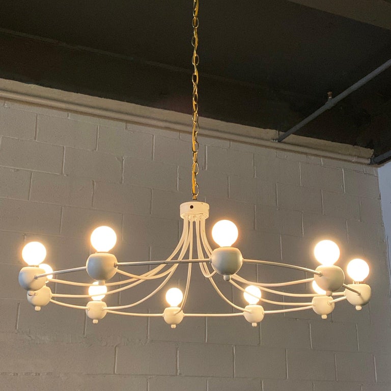 Mid-Century Modern, painted, wrought iron, circular chandelier features 10 sloping arms that accept chandelier base bulbs. The chandelier is newly wired with 40 inches of brass chain and matching canopy. Looks wonderful hanging low over a dining