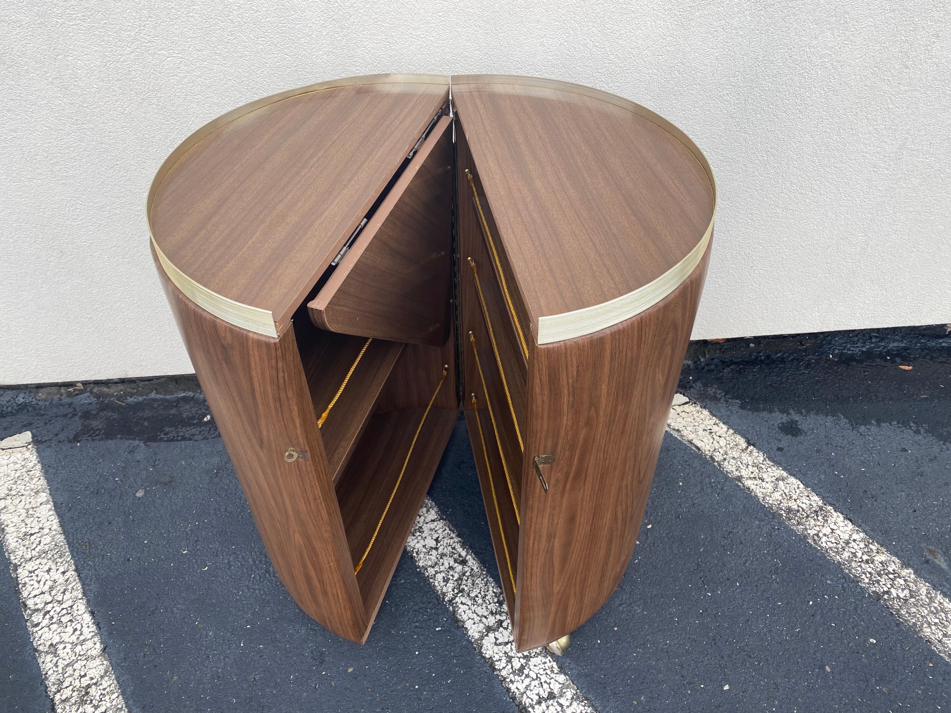 Mid-Century Modern circular rolling bar- Expandable. Bar cabinet has a circular shape in closed position and expands into a serving bar cabinet with connecting fold-out surface. Bar has vinyl fabric with wood-look pattern on its outer and interior