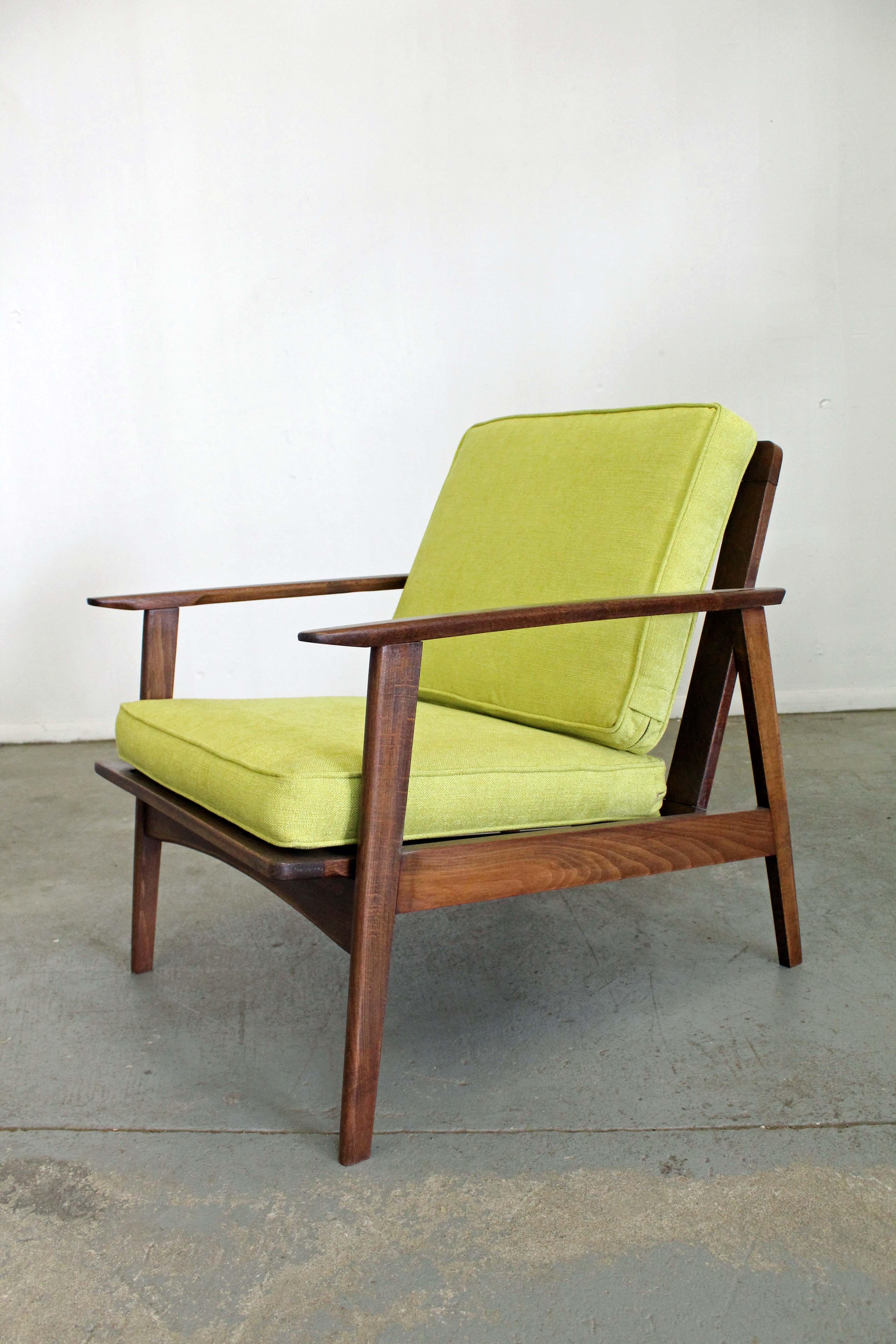 Offered is a Mid-Century Modern open arm lounge chair. This piece is made of walnut and has been reupholstered with 'citron' fabric. The chair comes apart for easy shipping and storage. It is in excellent condition for its age (reupholstered,