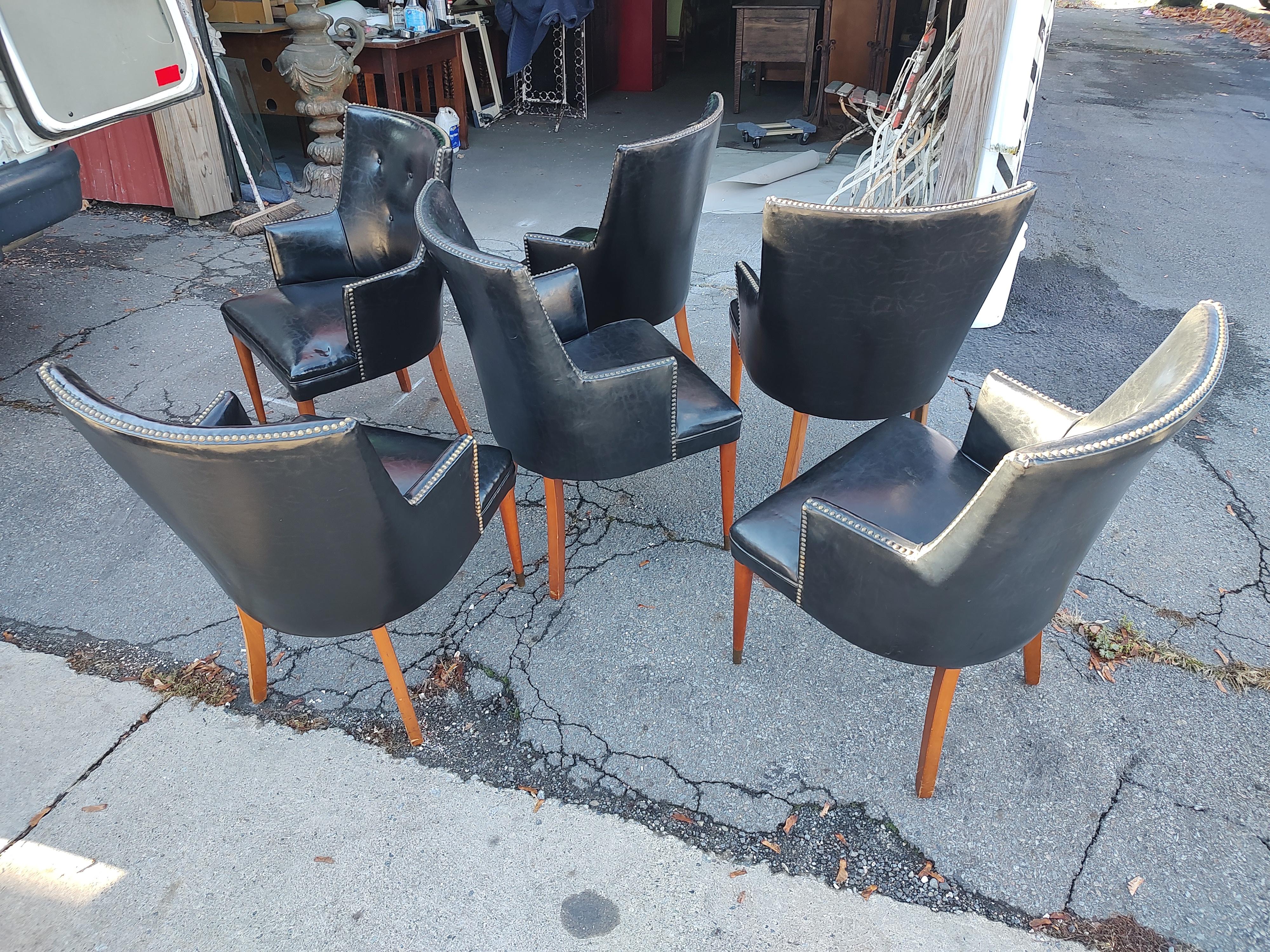 Fabulous set of six faux leather ( Naughahyde ) in black with nailhead trim. Tucked back arms on all six to ensure they work around a dining room table. Comfy and easy to care for. In excellent vintage condition with minimal wear. All original. Legs