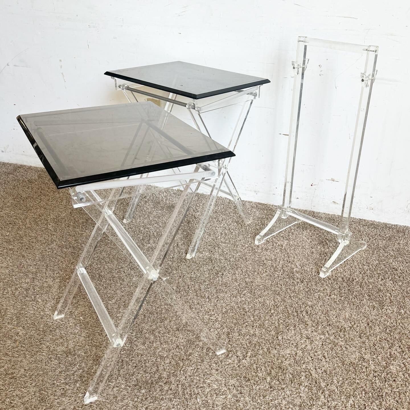 Rediscover the elegance of the mid-century era with this Mid Century Modern Clear and Smoked Lucite Gold Up Tray Table Set. Featuring a unique blend of clear and smoked lucite with gold accents, these tables provide a retro yet sophisticated vibe.