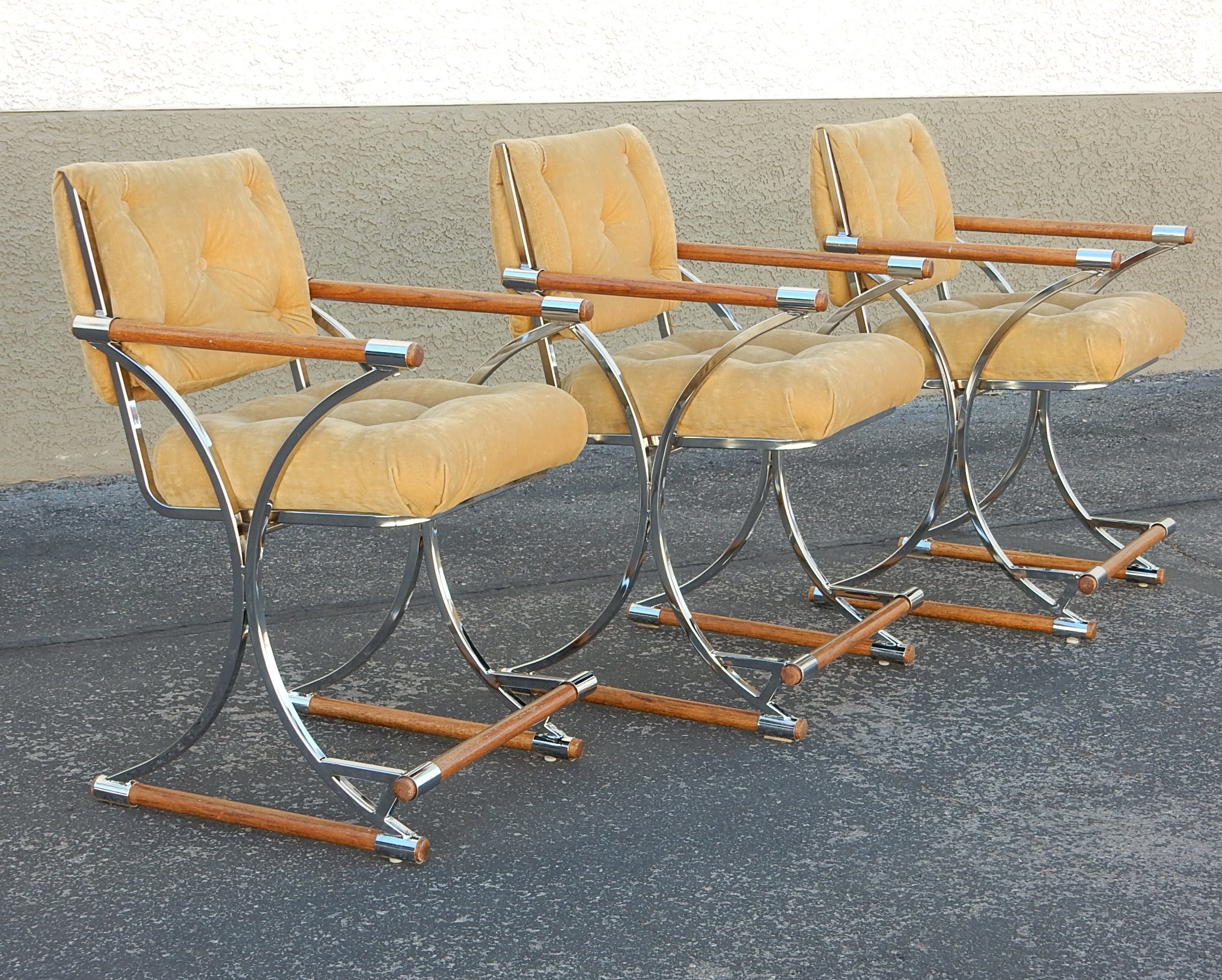 Exceptional quality crafted barstools in the manner of Cleo Baldon, circa 1970's.
Thick sculpted steel frames, triple chrome plated with dowel wood arms, feet and kick rail.
Solid, very comfortable and gently adult pre-owned with no structural