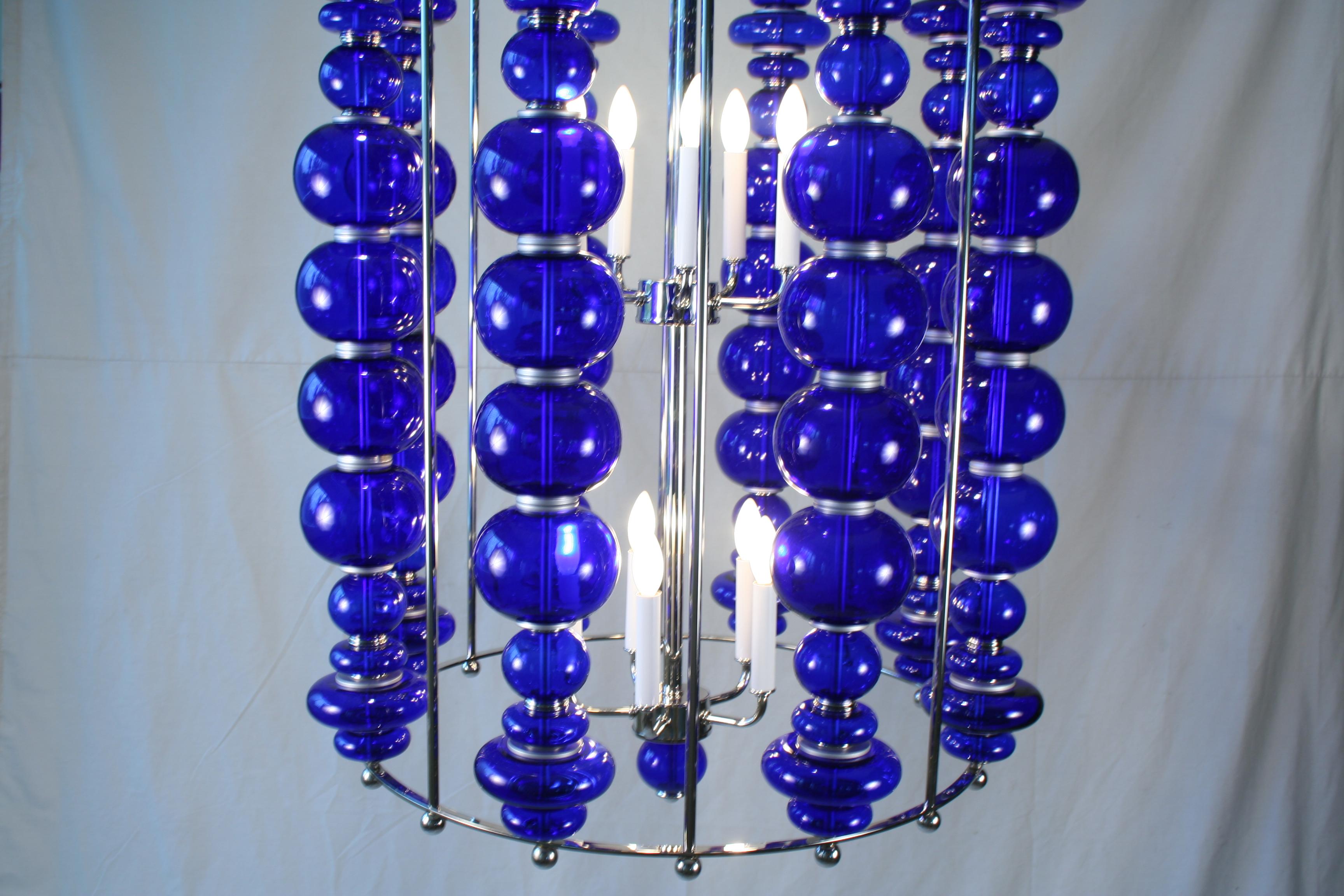 Custom designed and custom made modern chandelier. Cobalt blue glass spheres made in India. shades in 4 different shapes all stacked to form a circle of Blue. On Hi-polished nickel frame made of brass and steel. Double light cluster bodies with