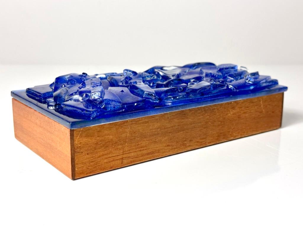 Striking glass lidded trinket or jewelry box by Robert W Brown circa 1960s
Teak construction with cobalt blue sculptural fused glass inset top

8