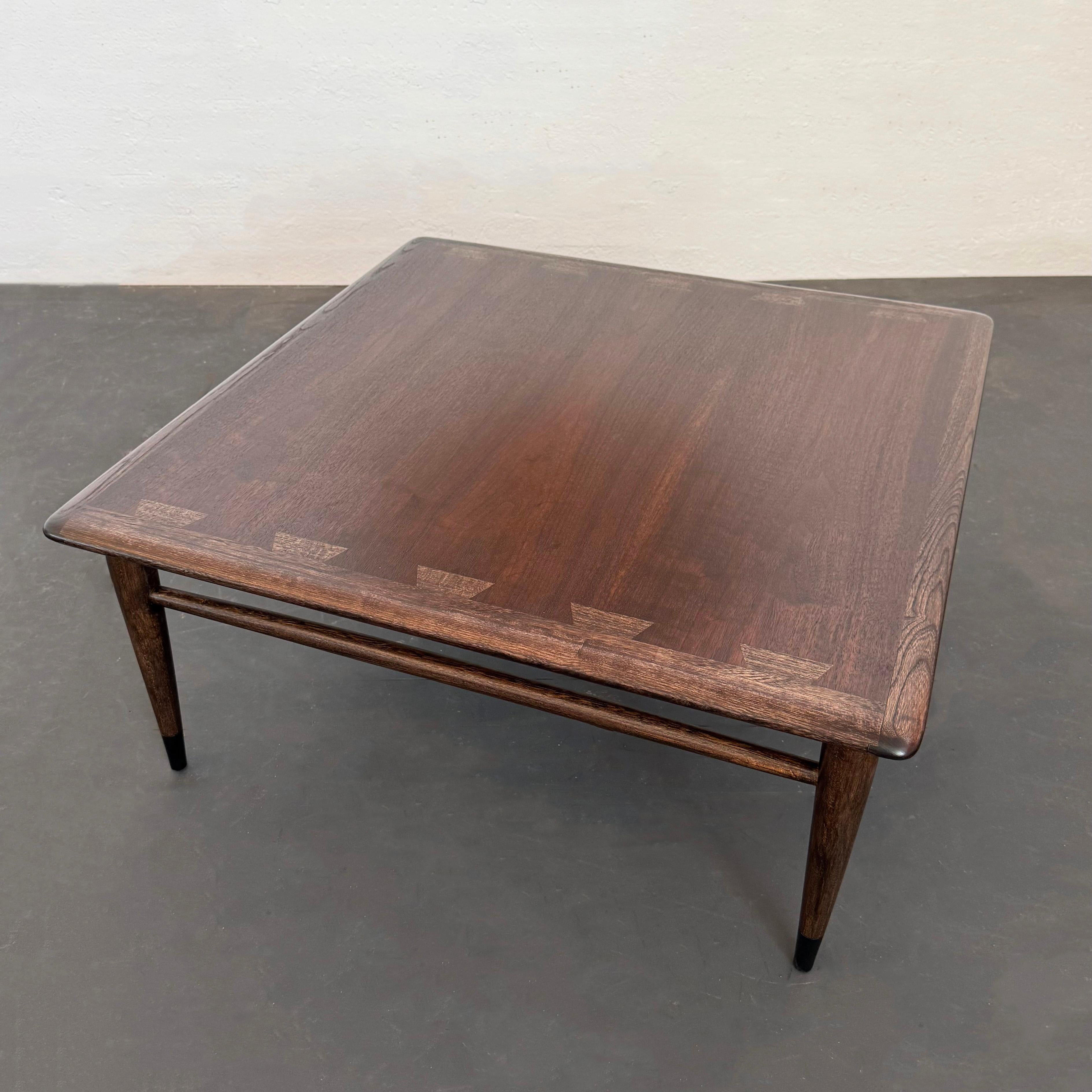 This square walnut and ash coffee table is model no. 900-17 designed by Andre Bus for Lane Furniture's 