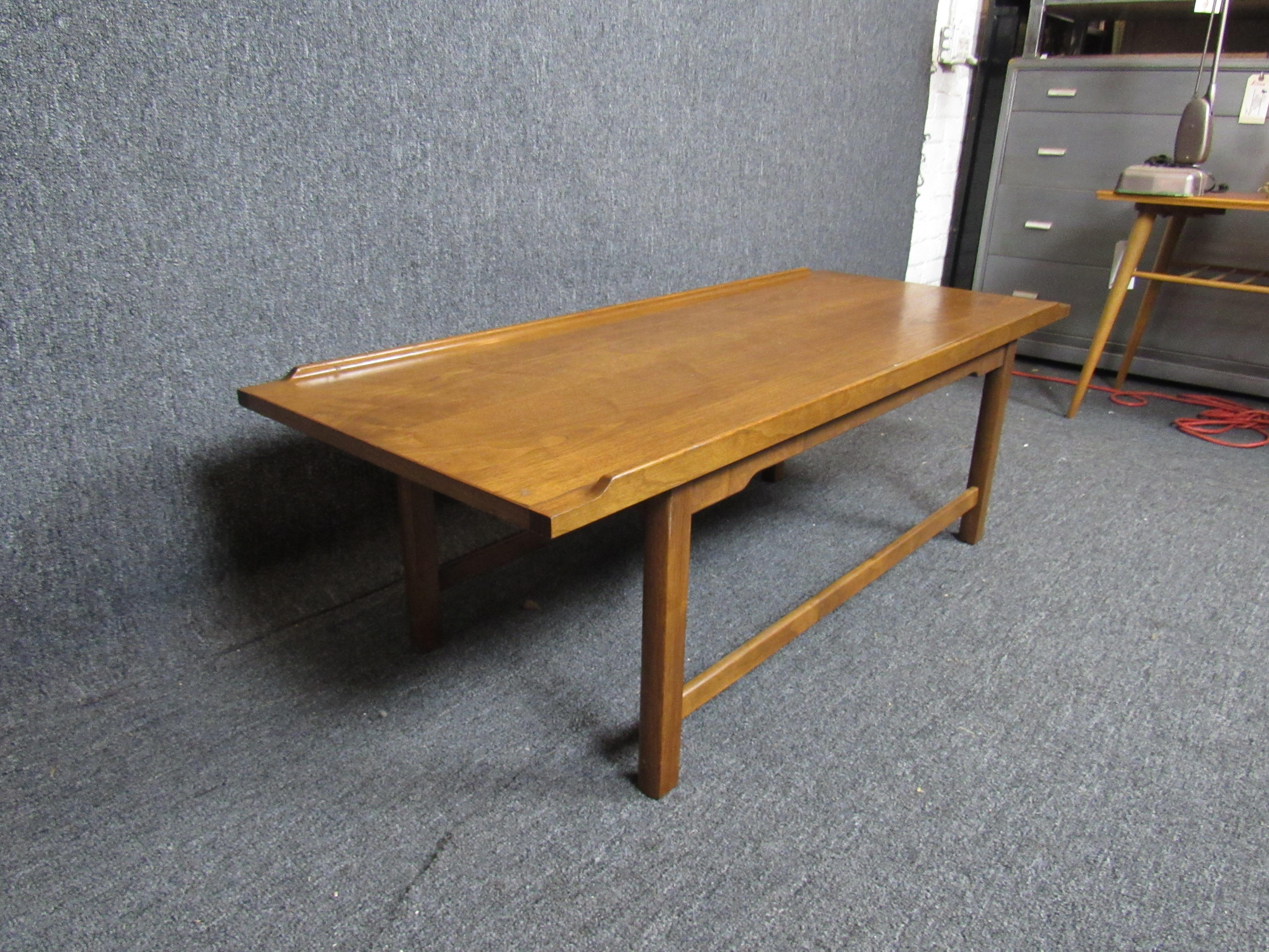 Beautiful mid-century coffee table made by the Drexel furniture company in North Carolina. An ample tabletop with sculpted raised edges highlight the wood's warm, natural grains. A very versatile table sure to tie together any home or office.