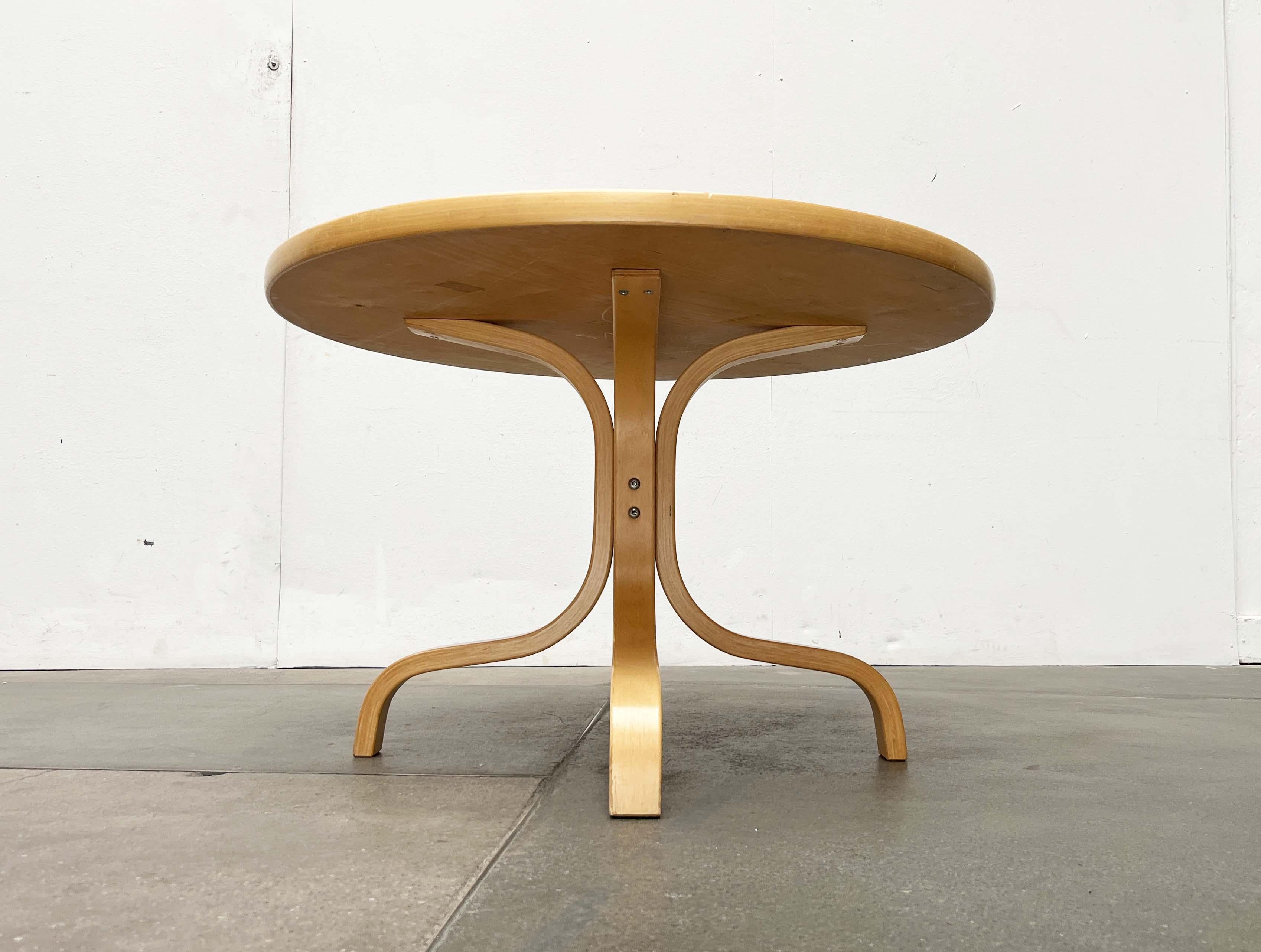 Table basse du fabricant finlandais Asko, conçue par Ilmari Lappalainen dans les années 1960.

Un design simple et fonctionnel avec une base distinctive. La base en étoile frappante est composée de quatre éléments en bois courbé élégants. Le plateau