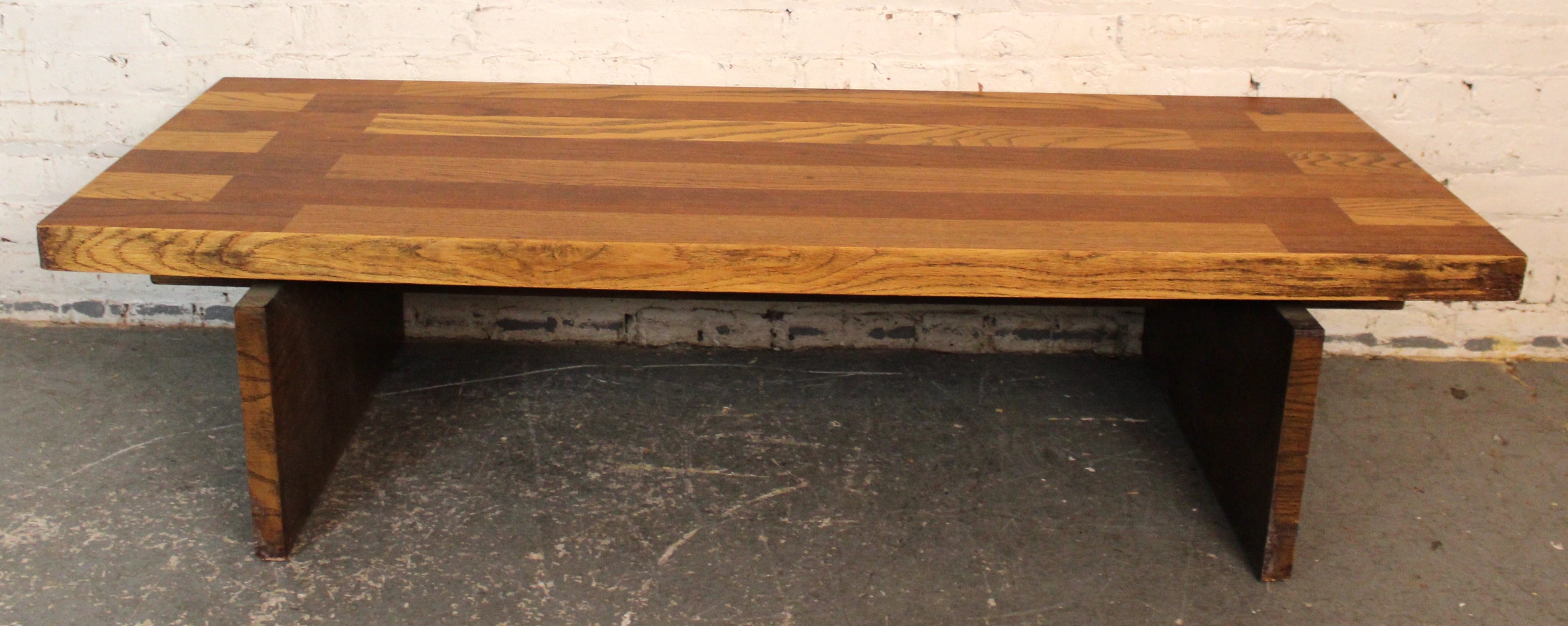 Striking butcher block style mid-century coffee table by Lane Furniture, featuring a semi-parquet oak top with rich wood grain and geometric patterning. The solid trestle-style base offers architectural appeal and sturdy support, blending bold