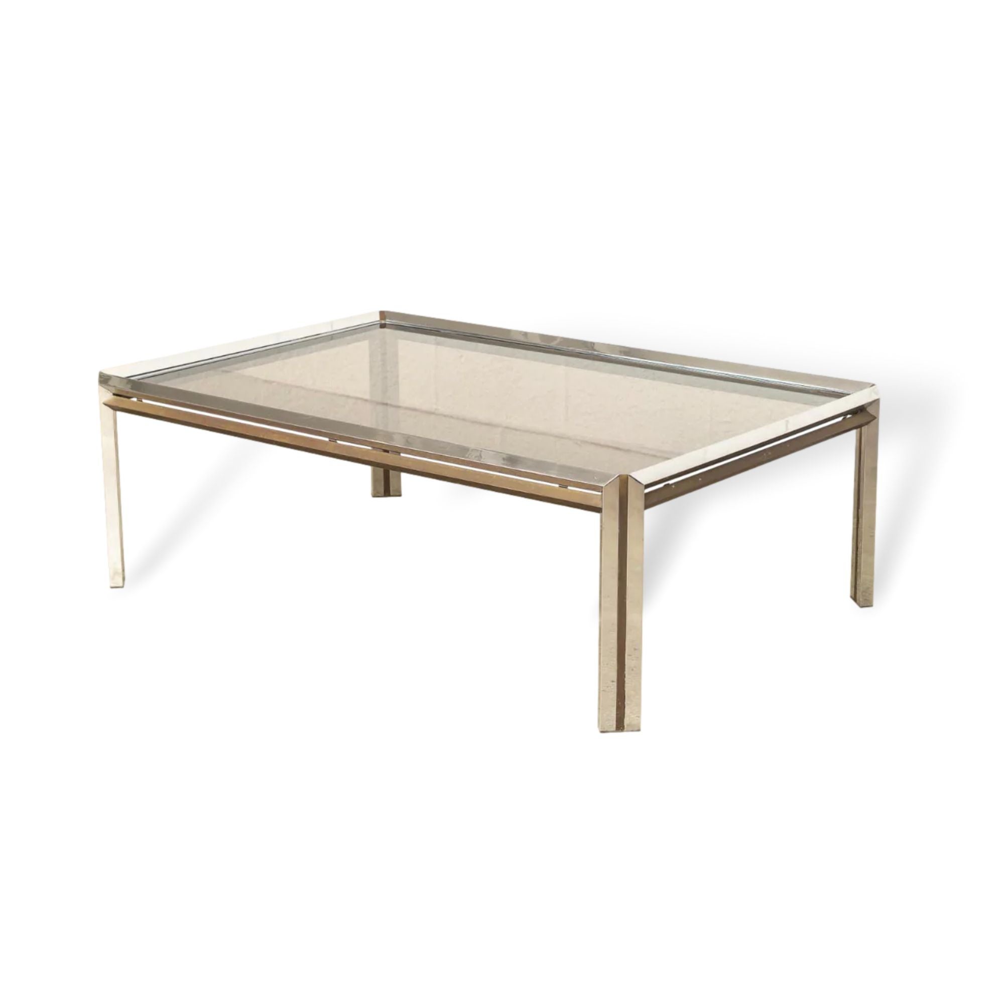 This Vintage Mid-Century Modern chrome, brass and glass rectangular coffee table in the style of Milo Baughman is circa 1970. The unique design features a faceted chrome frame accented by solid brass side bars and inlaid brass striped legs. The