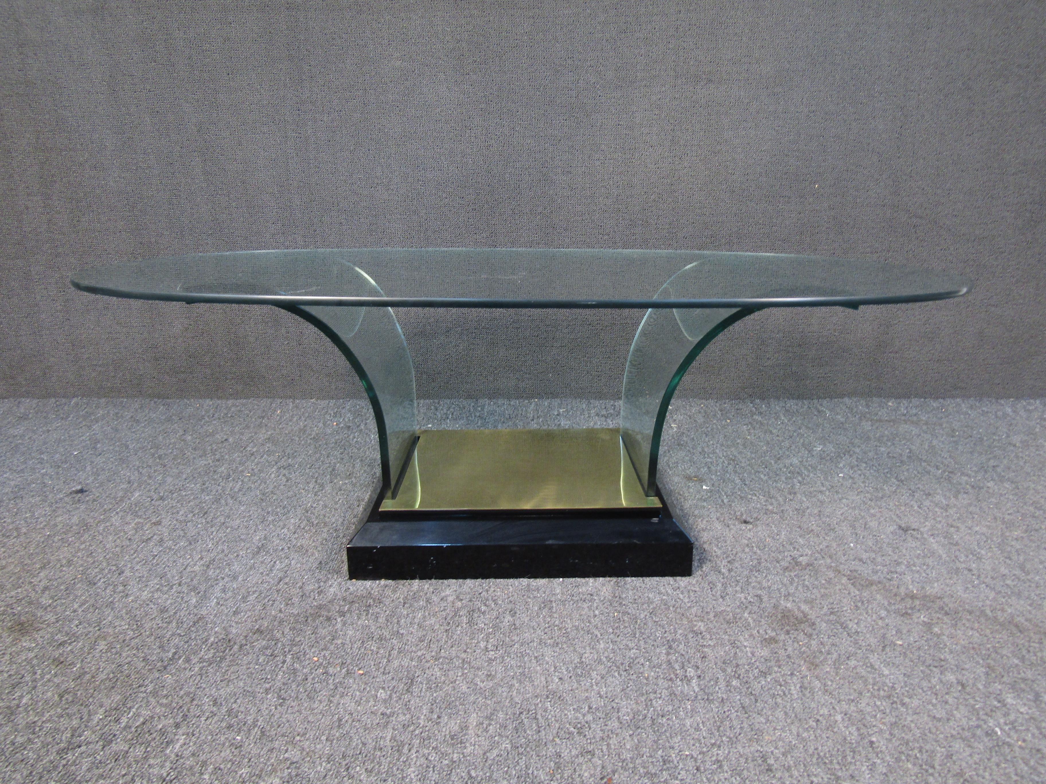 With an oval glass top and glass supports curving into a brass base, this vintage coffee table is sure to impress. Please confirm item location with seller (NY/NJ).