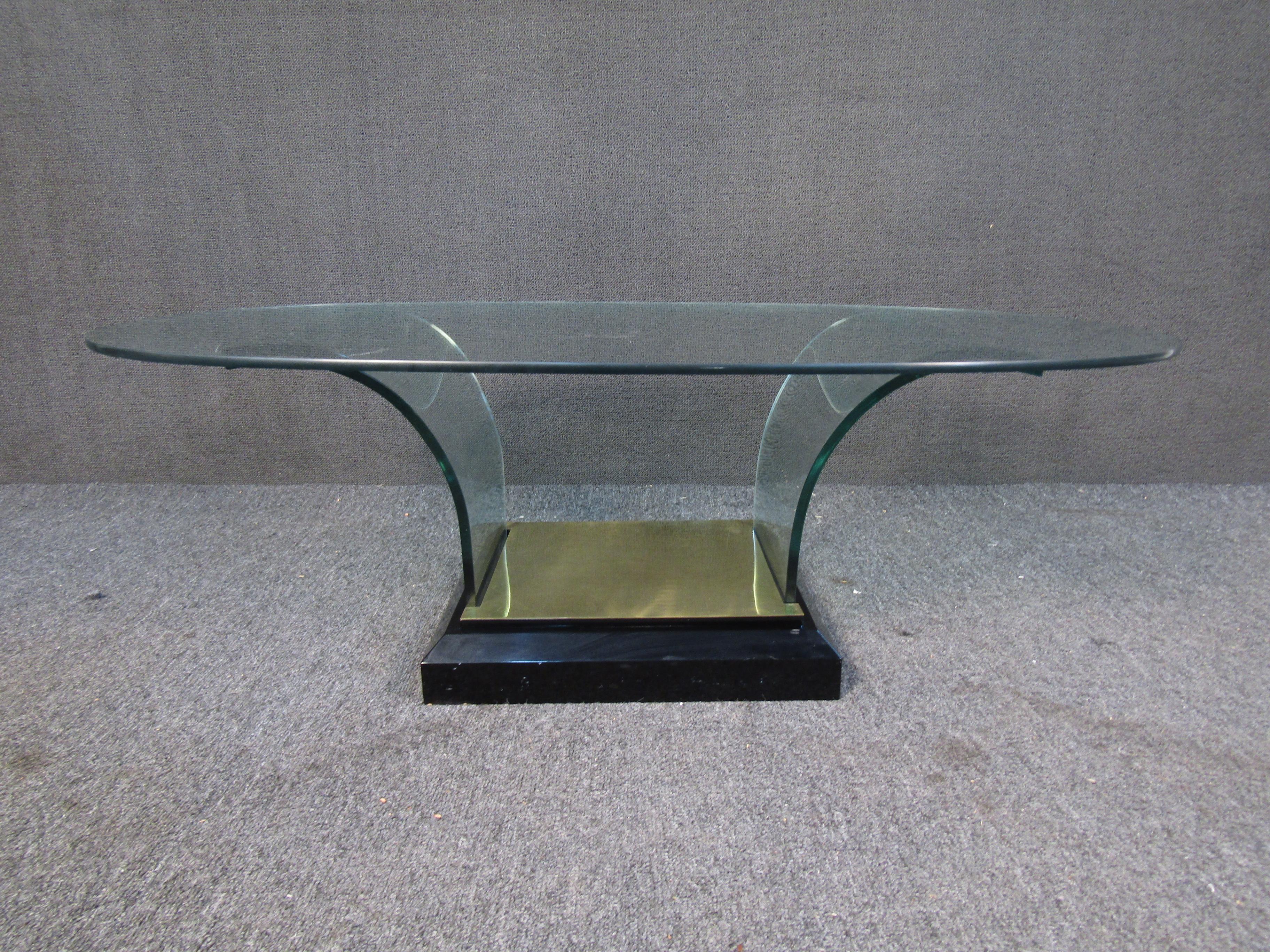 Avec un plateau ovale en verre et des supports en verre s'incurvant dans une base en laiton, cette table basse vintage ne manquera pas d'impressionner. Veuillez confirmer la localisation de l'objet auprès du vendeur (NY/NJ).