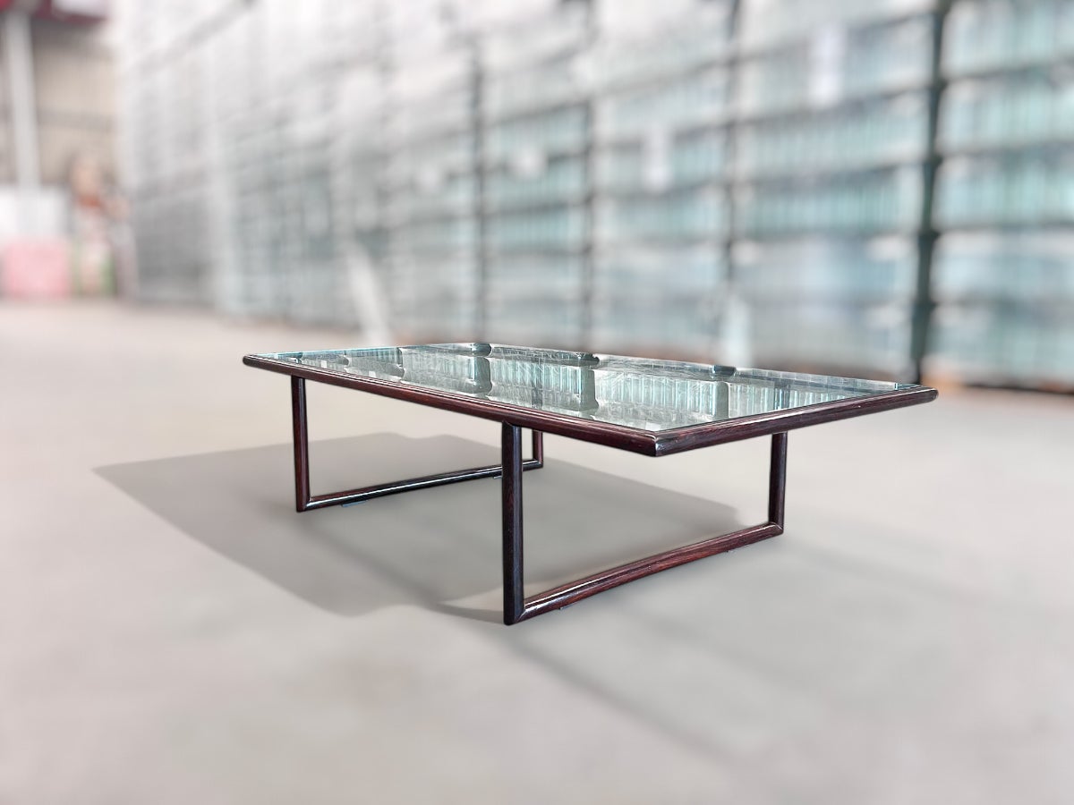 Disponible aujourd'hui, cette table basse moderne du milieu du siècle en bois de rose et verre, Joaquim Tenreiro, vers les années 1960, n'est rien de moins que spectaculaire. 

Conçue par Joaquim Tenreiro (1906-1992) dans les années 1940 et produite