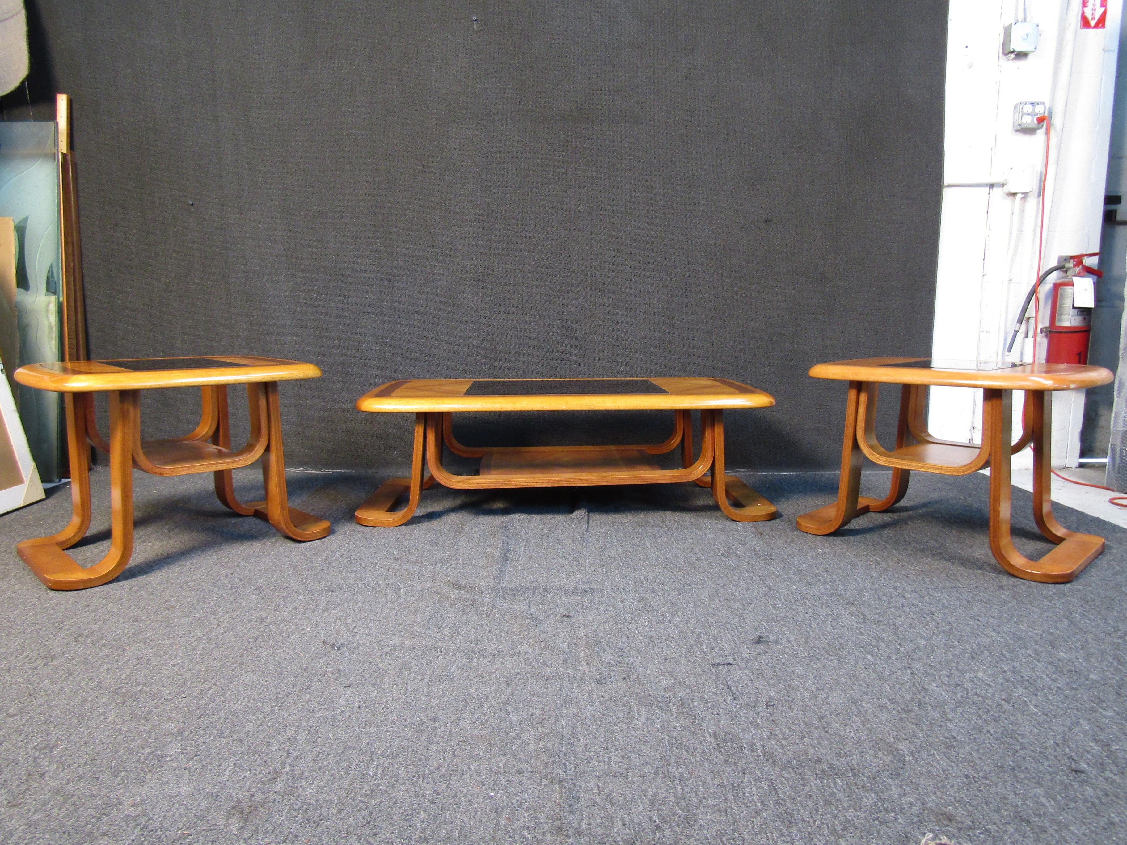 Cet ensemble unique de table basse comprend une table basse large et deux tables d'appoint plus petites. Un design unique comprend des incrustations en verre foncé, des motifs courbes inhabituels sur la base et des motifs en forme de diamant en
