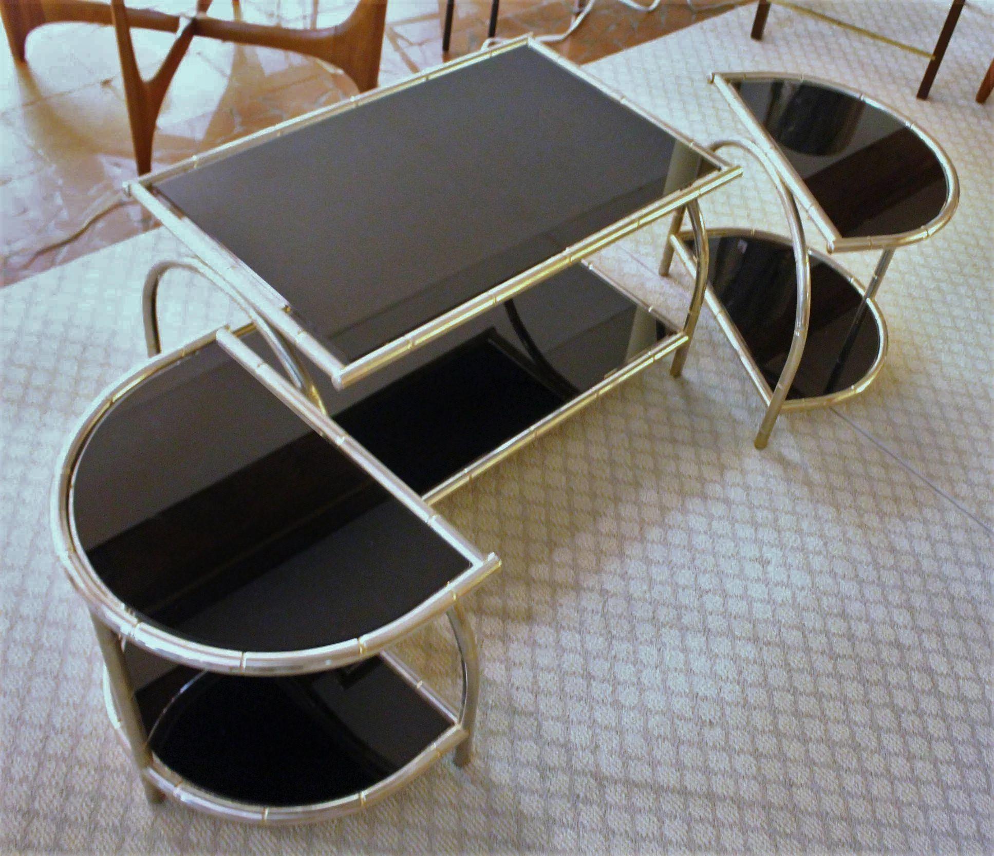 Un ensemble incroyablement élégant de 2 tables d'appoint avec table basse, datant de C.I.C. des années 1960, pouvant être utilisées séparément ou ensemble comme une grande table basse ovale. Faux bambou de chrome avec surfaces en verre fumé. 
31 3/4