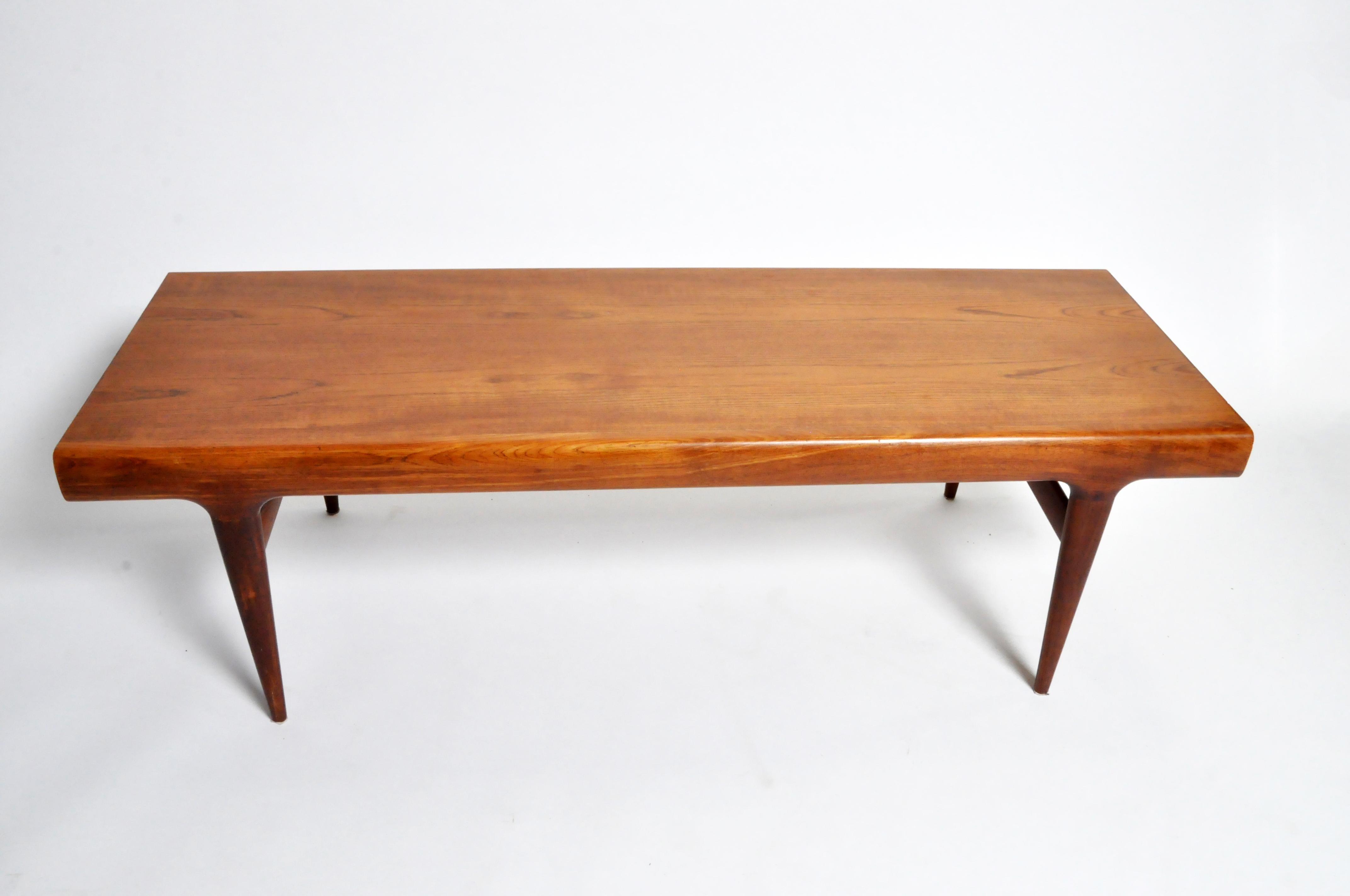 This sleek and very simple Danish, modern, table has a solid teak frame and teak veneer top. The solid hardwood legs are elegantly tapered. One end features a drawer and the other end features a pull-out surface extension.
