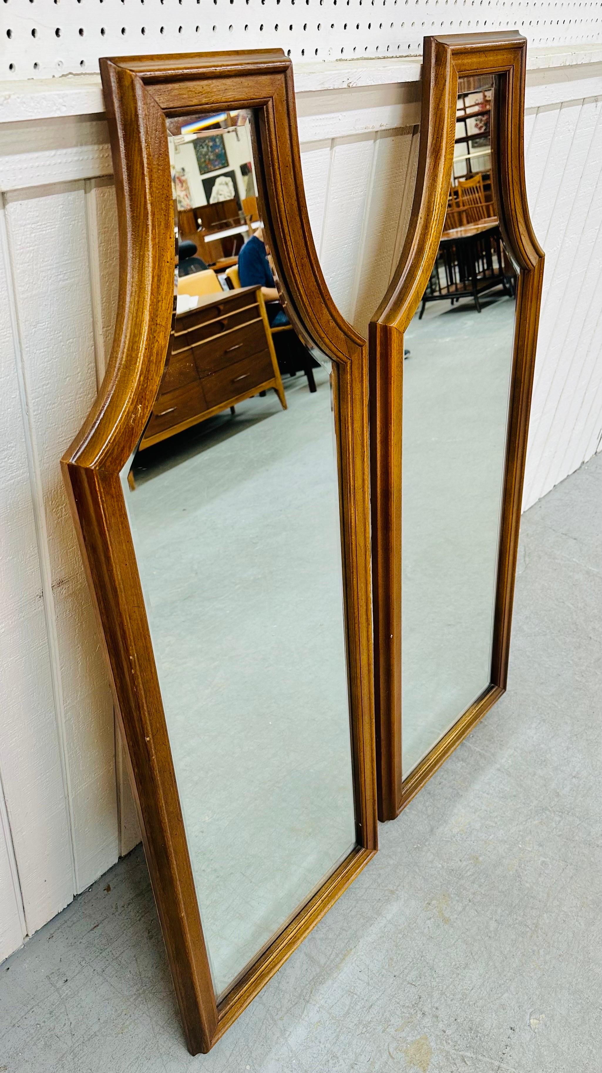 This listing is for a pair of Mid-Century Modern Walnut Wall Mirrors. Featuring a gothic coffin design, beveled mirror, and a beautiful walnut finish. This is an exceptional combination of quality and design!